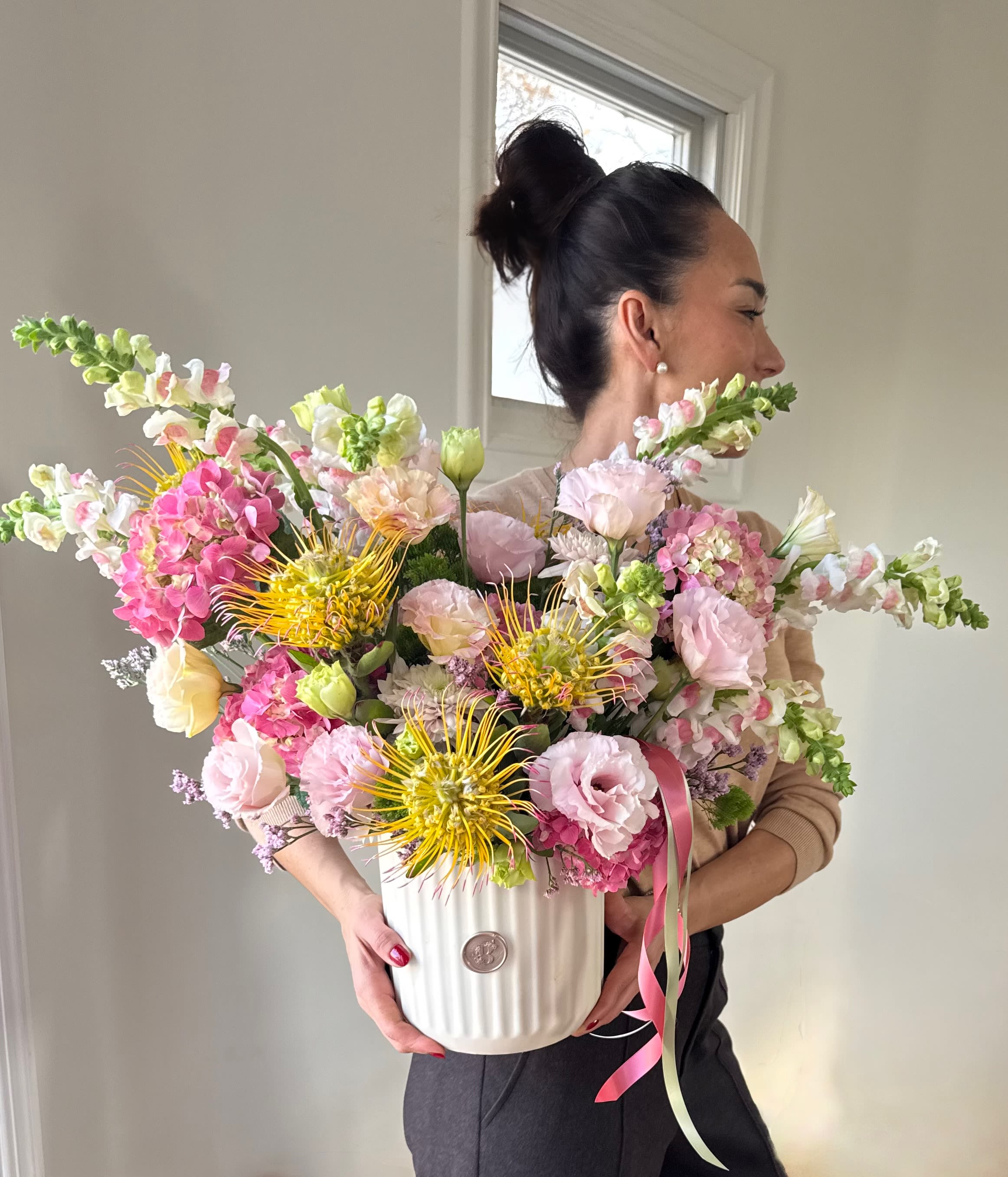 Garden Sonata - Garden Sonata is a refined, artistic arrangement inspired by the rhythm and harmony of a blooming spring garden. Designed in soft pastel tones with gentle pops of warmth, this composition blends delicate petals with textured accents for a look that feels both romantic and modern.  Each arrangement is thoughtfully created using the finest seasonal blooms available, allowing every piece to feel unique while maintaining the same elevated style, fullness, and movement shown in the reference image. Designed in a sculptural vessel, Garden Sonata makes a striking statement for celebrations, thoughtful gifts, or to brighten any space with effortless elegance.  Please note: Flower varieties and shades may vary slightly based on seasonal availability, while the overall color palette, size, and aesthetic remain true to the design.