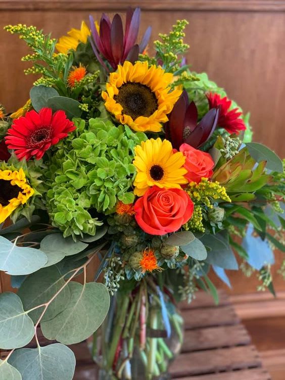 Fall Bright and Cheery - Bright colorful blooms in a sleek glass cube. This arrangement is perfect for any occasion. Colors and varieties will vary with the season.