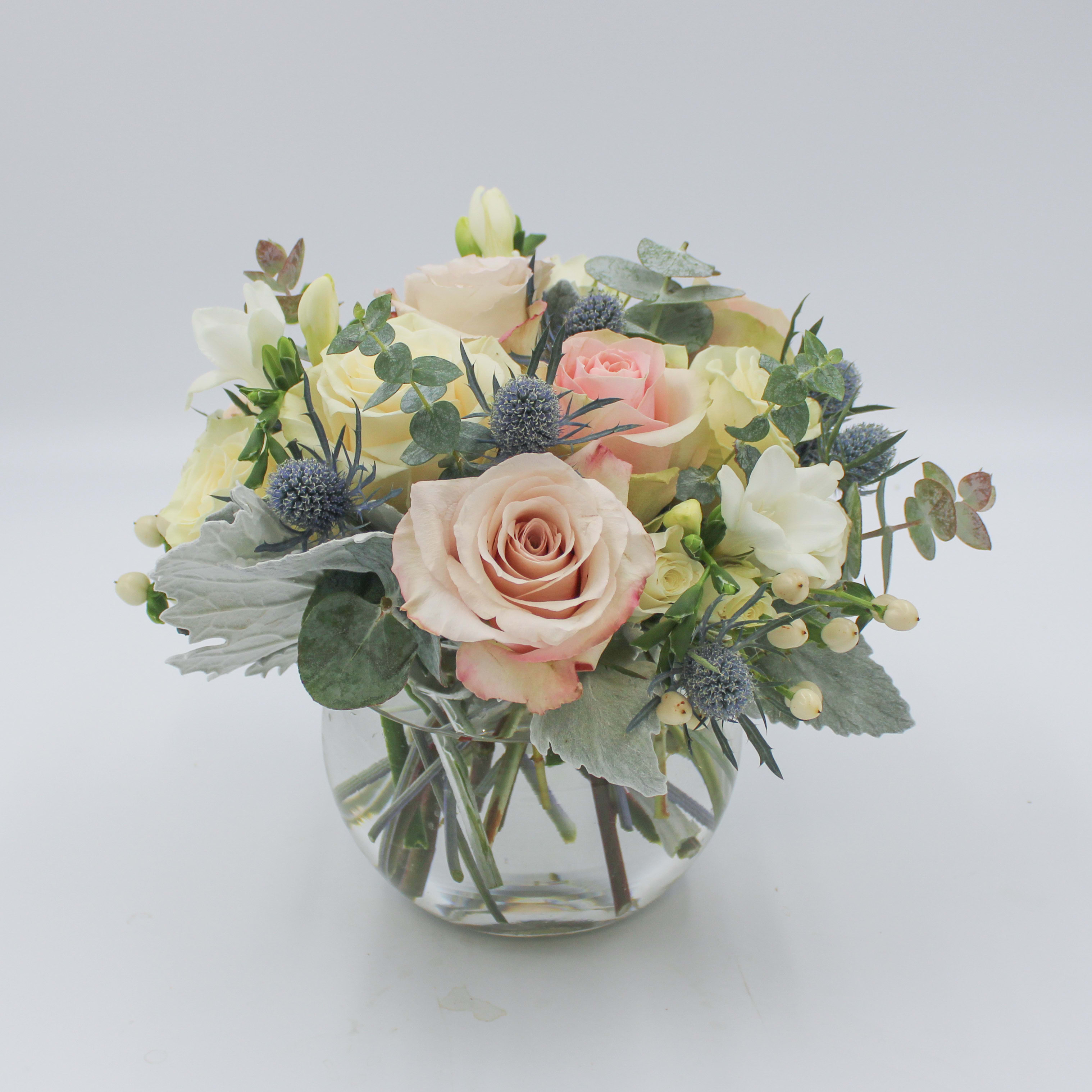 Swiss Alps - Swiss Alps is a luxurious display of neutral and blush toned Roses with textured hints of grays and blue arranged in a clear glass bubble bowl. Swiss Alps includes Quicksand Roses, White Roses, Blush Roses, White Spray Roses, Dusty Miller, Blue Thistle and more. The Standard and Deluxe Swiss Alps is designed in a 6 inch Bubble Bowl and the Premium Swiss Alps is designed in an 8 inch Bubble Bowl.
