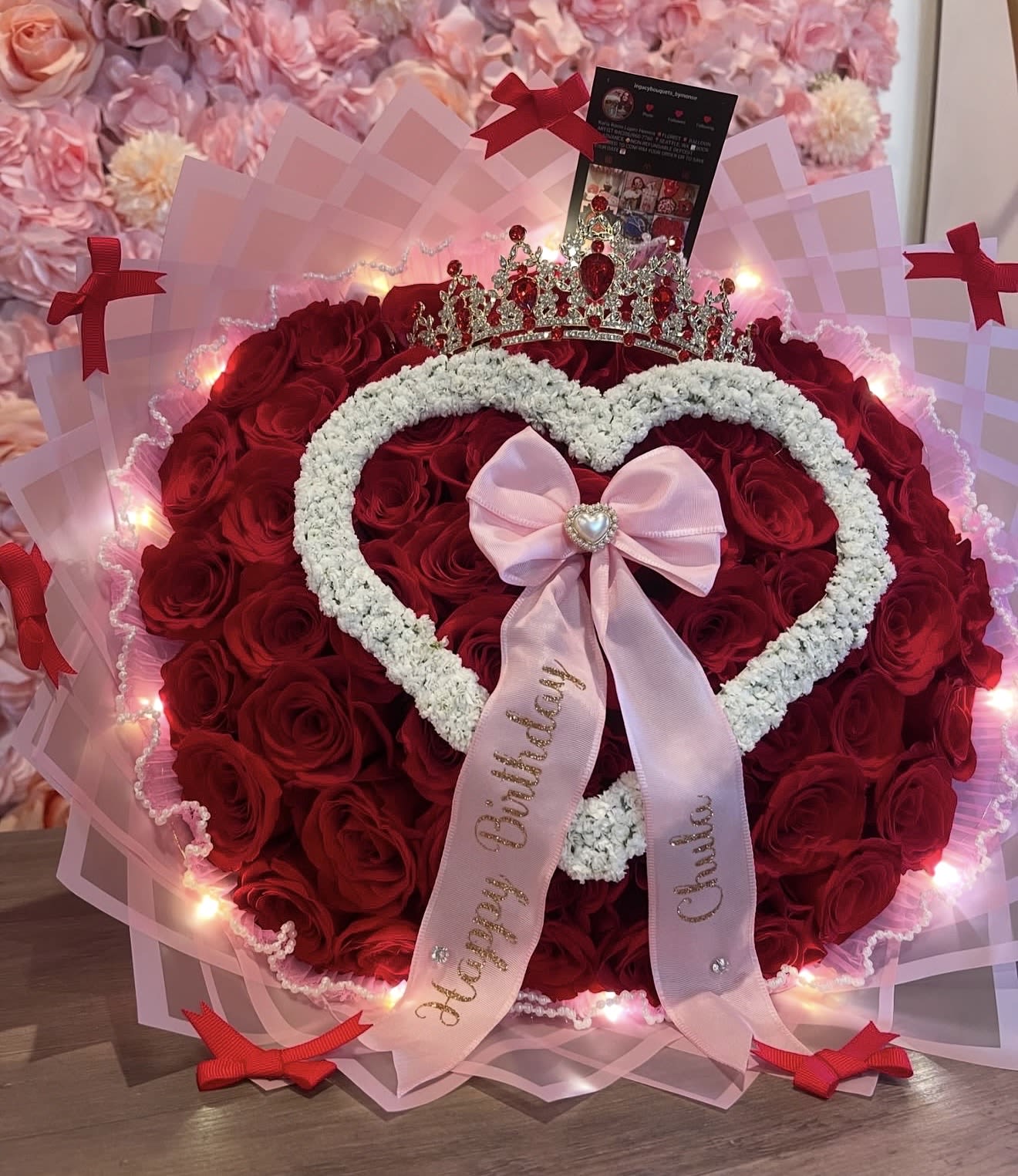 Chula Bouquet - This is all you need to make that special person fall in love. Surprise her with this beauty.  -50 to100 Red Premium Ecuadorean Roses.( rose ct depends on size selected) -Custom Ribbon Bow (wording of your choice.) -Pearl Mesh with fairy lights as a rim.  -White baby’s breath open heart topper. -Red and Gold tiara  -Pink wrapping paper with bows to enhance your bouquet.   “NOTICE”  We are dedicated to delivering your emotional sentiments with the utmost care, ensuring that each arrangement is fresh, beautiful, and arrives on time. Due to the natural variability of flowers, as well as seasonal and regional availability, substitutions may occasionally be necessary. Rest assured, any substitutions will be of equal or greater value, and we will make every effort to preserve the overall design, including the shape, size, style, and color combinations of the arrangement. In the case of single-variety arrangements, the specific variety will take precedence over color to maintain the intended look and feel. Thank you in advance for understanding that flowers are a natural product and may vary slightly in appearance.