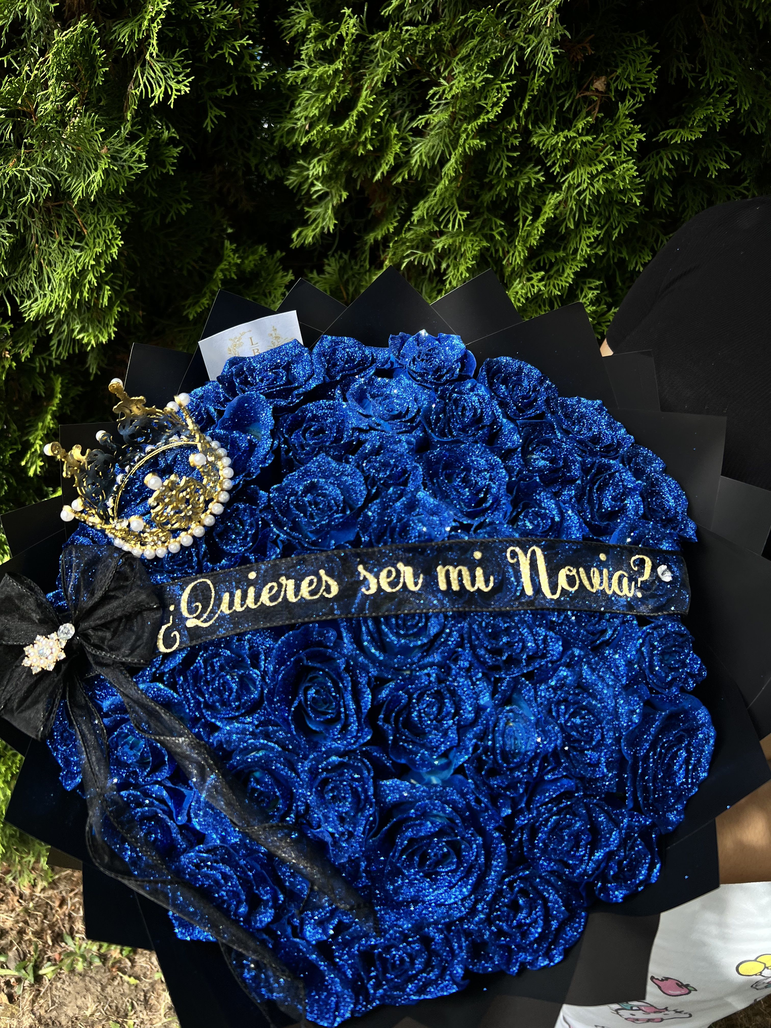 Be my GF Bouquet - If you’re looking for the perfect bouquet to propose and ask to be your girlfriend and gift her something unique and beautiful, this is your perfect way to propose.  - 50 to 100 tinted Blue roses topped with blue glitter.(rose ct depends on size selected.) -Custom ribbon Will you be my Girlfriend or Quieres see mi Novia) - Small Crown     “NOTICE”  We are dedicated to delivering your emotional sentiments with the utmost care, ensuring that each arrangement is fresh, beautiful, and arrives on time. Due to the natural variability of flowers, as well as seasonal and regional availability, substitutions may occasionally be necessary. Rest assured, any substitutions will be of equal or greater value, and we will make every effort to preserve the overall design, including the shape, size, style, and color combinations of the arrangement. In the case of single-variety arrangements, the specific variety will take precedence over color to maintain the intended look and feel. Thank you in advance for understanding that flowers are a natural product and may vary slightly in appearance.