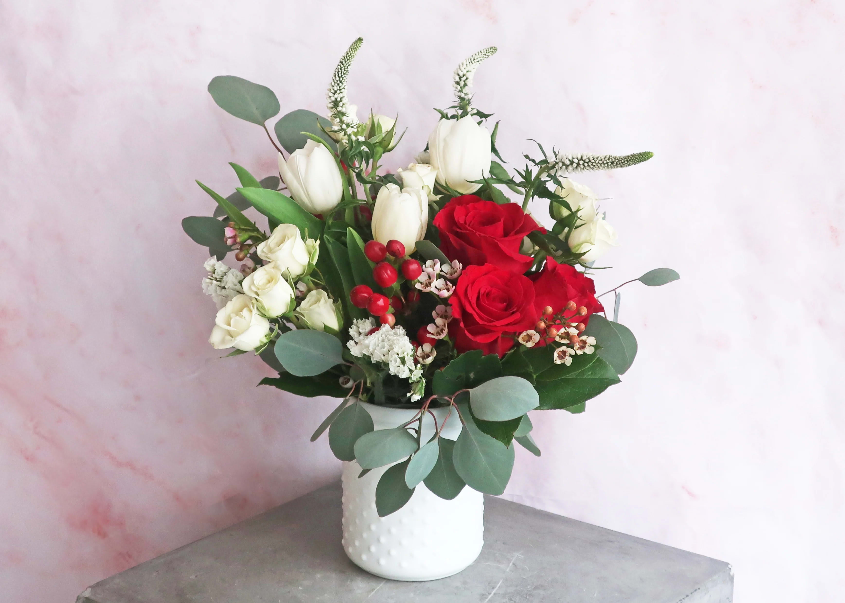Sweet Bliss - A white hobnail vintage-style vase filled with timeless red and white blooms like roses, tulips, spray roses and berries. A sweet floral surprise for a friend, partner or family member.   Arrangement is approximately 10" tall and 7" wide.   COVID NOTICE: Due to an international shortage of flowers and vases and floral supply chain issues, it may be necessary to substitute similar flowers and the vase used in this design. We always strive to create a design as close as possible to the design shown. If you have any questions regarding these changes, please call and talk to a team member before placing your order, (703) 779-3530.