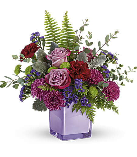 Purple Serenity Bouquet - Are you looking for a bouquet that makes a statement yet harmonizes into the interior of your home perfectly? Well, look no further than the Purple Serenity Bouquet! The lavender-colored roses paired with maroon blooms that are balanced out with the greens are all tied in together with an amethyst-colored cube - it's the perfect addition to your home as well as the perfect touching gift to a friend!   This bouquet features gorgeous pinky-lavender colored roses, bright red carnations, and cute pink chrysanthemums that are truly balanced out with the greenery.  Approximately: 16 1/4" W x 14 1/2" H  Orientation: All-Around