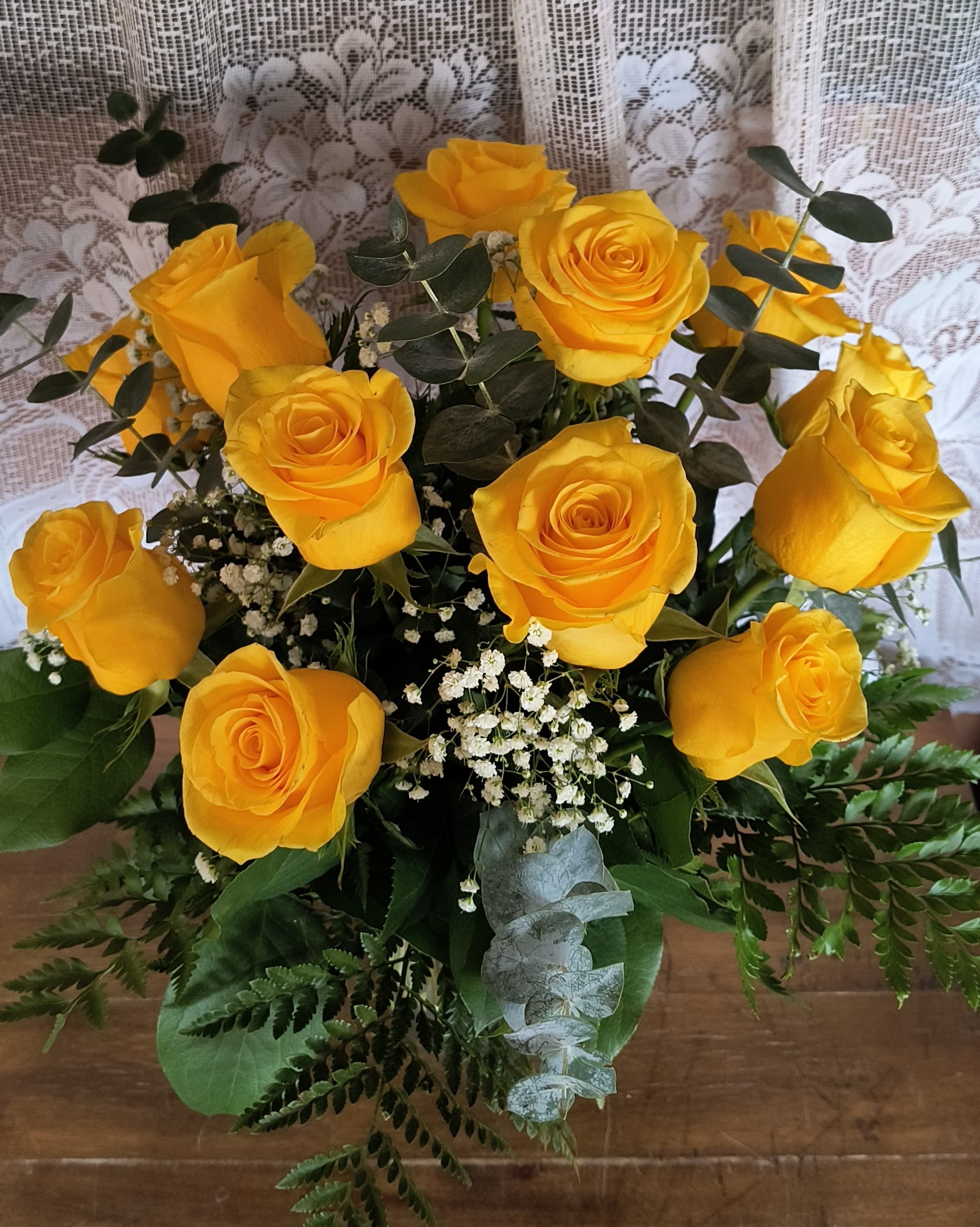 Sunshine Deluxe - Sunshine yellow roses are sure to brighten any ones day. These sunny yellow roses are accented with wax flower and assorted greenery all in a glass vase.