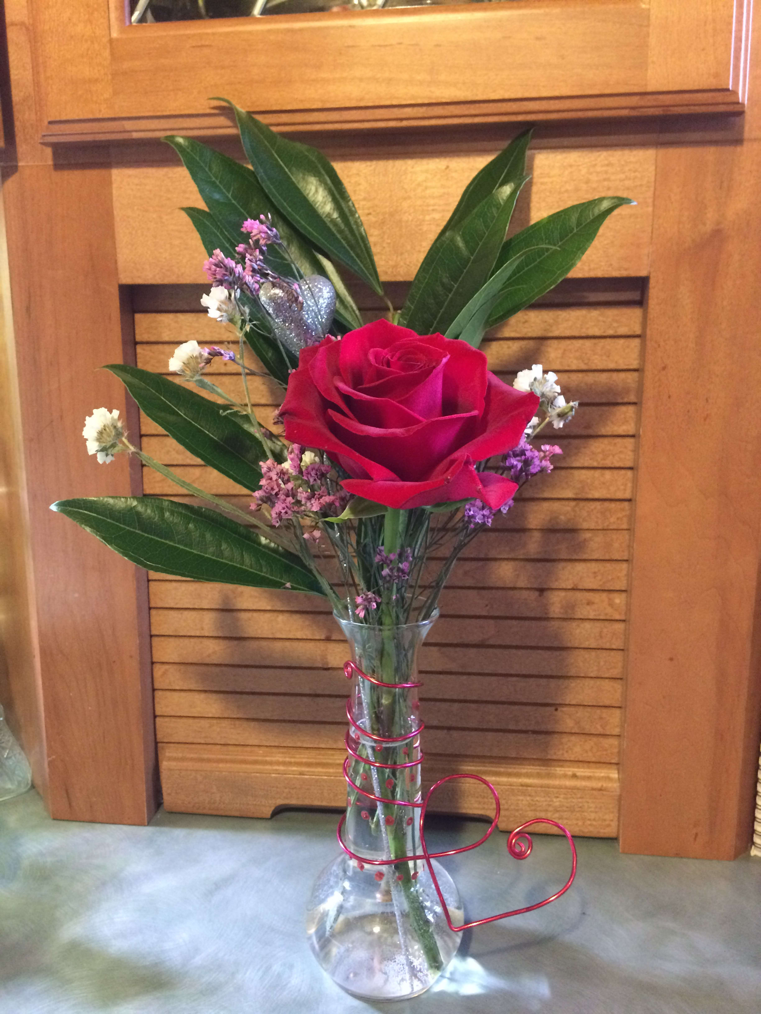 Your my One and Only - Single rose inside a one of a kind custom created wire and glass painted stem vase with greenery and dried accents. (florists choice) Each vase will be slightly different, but will contain the the heart wire and painted dot pattern. (designer's choice of greenery, may vary from type shown.) *Premium will be a larger vase.  Substitution Policy In some instances, the florists photo may represent an overall theme or look and include a one-of-a-kind vase which cannot be exactly replicated. Although the actual bouquet may not precisely match the photo, its temperament will. Occasionally, substitutions of flowers or containers happen due to weather, seasonality and market conditions which may affect availability. If this is the case with the gift you've selected, the local florist will ensure that the style, theme and color scheme of your arrangement is preserved and will only substitute items of equal or higher value.