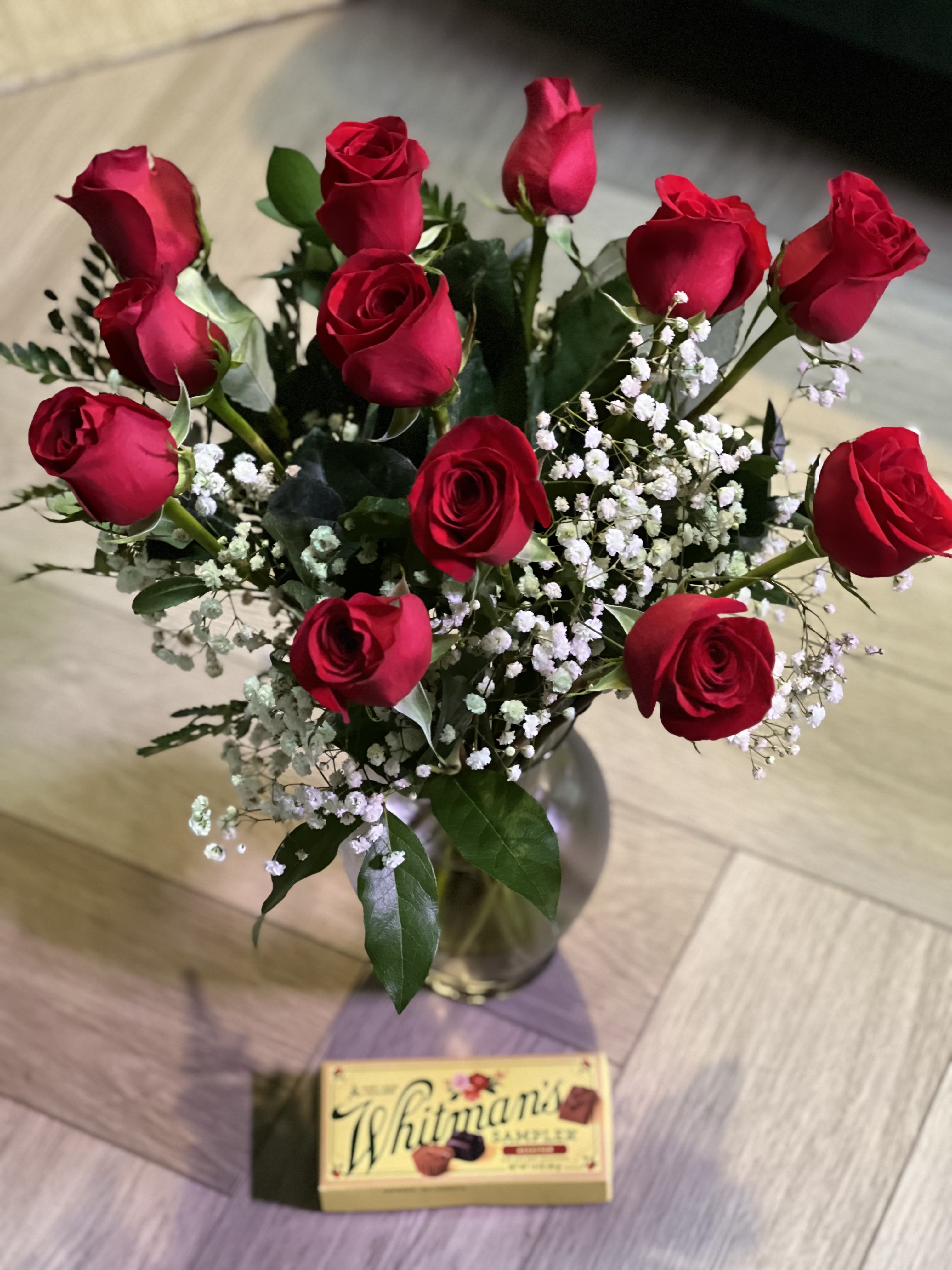 Roses with Chocolates  - A dozen red roses, in a clear vase with baby's breath and greenery with a Whitman's Sampler box of chocolates.