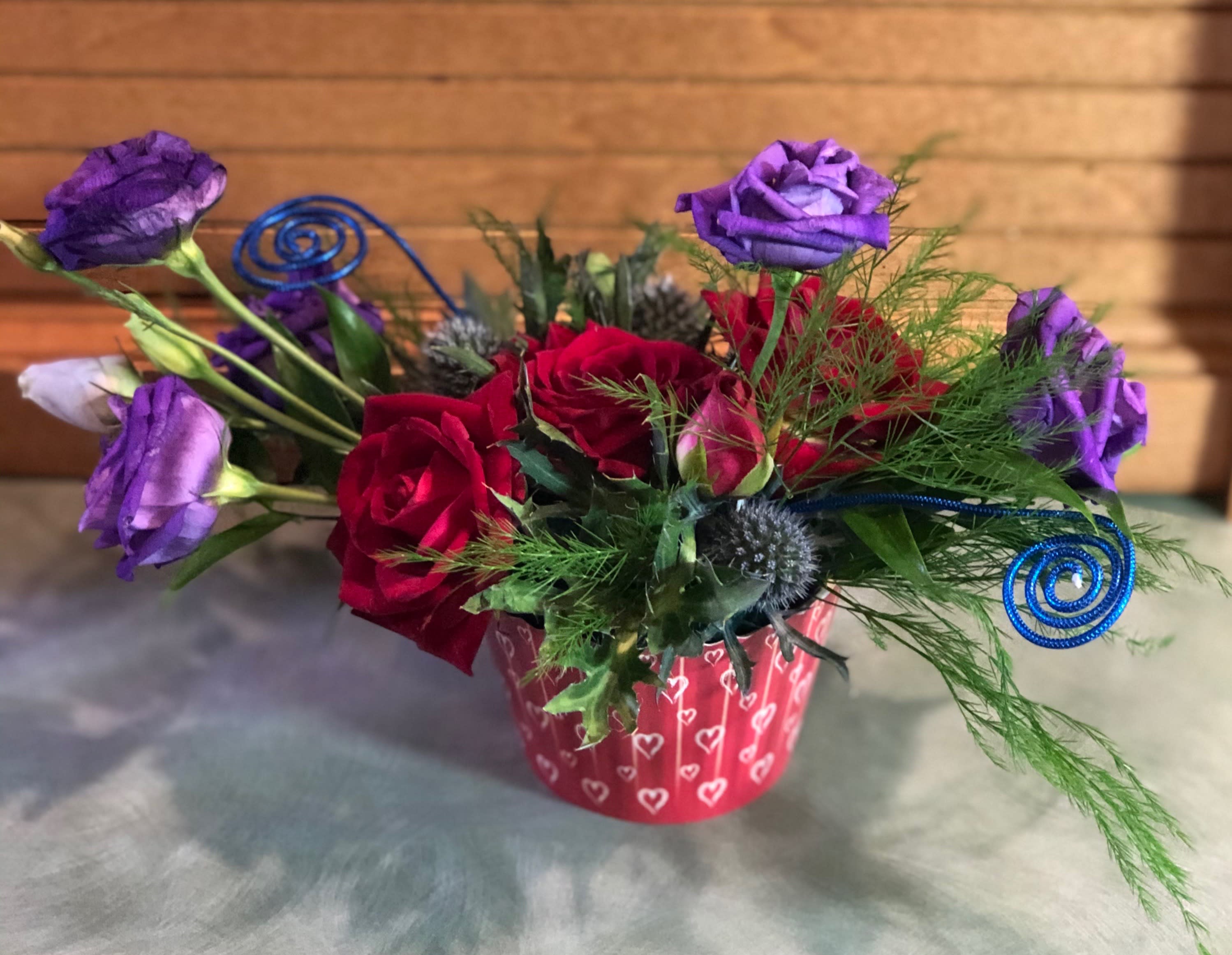 White Hearts on Red Cupcake -  Perfect size for just the right place. Small but mighty, our White Hearts on Red Cupcake design is just at home on your table or gracing your office space. It shows you are loved and thought about fondly. Lisianthus color may be different from one shown as stock is available.