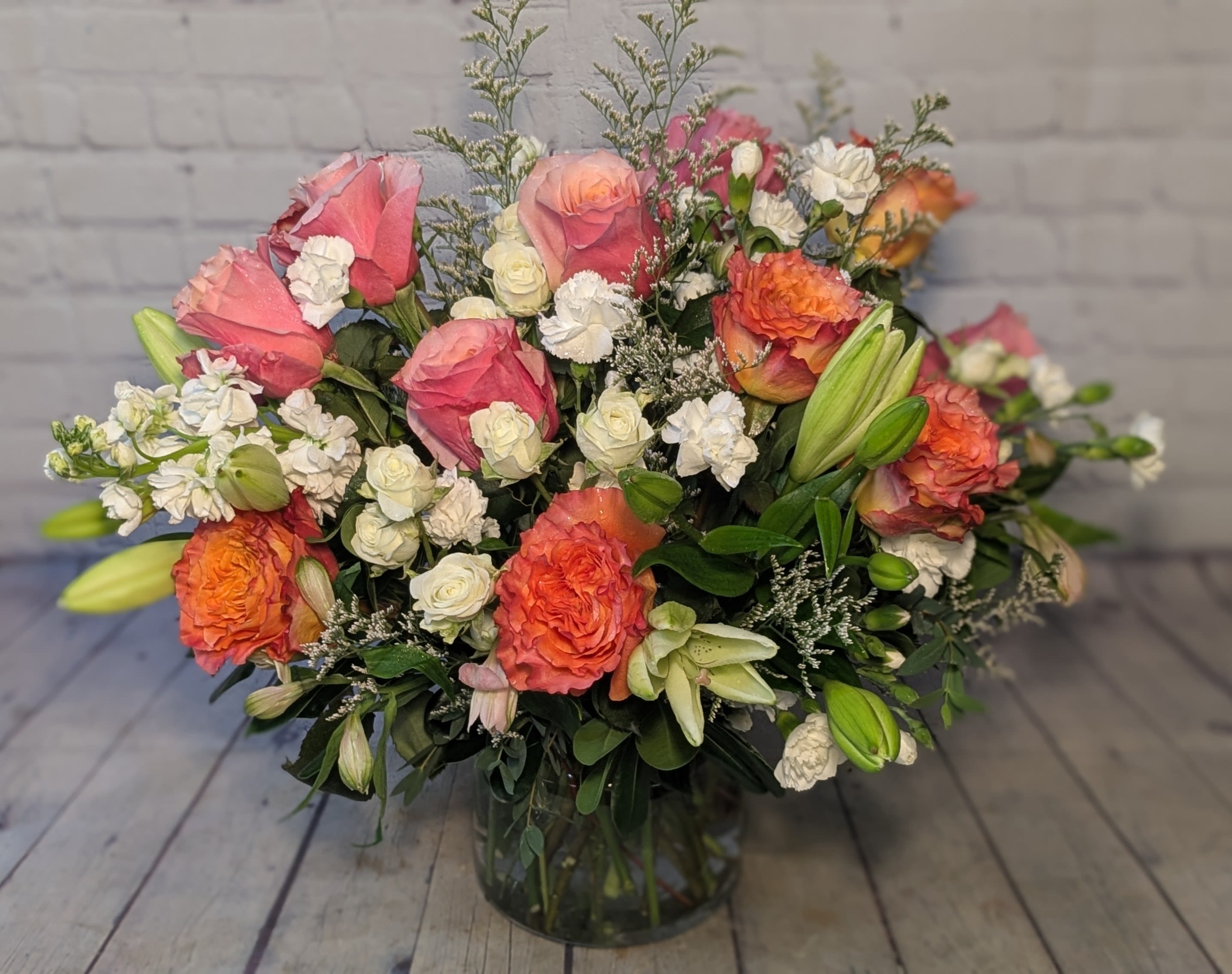 Evelyn - Meet "Evelyn" — a dreamy bouquet full of elegance and charm! Featuring soft coral and peach roses, creamy white blooms, and lush lilies just waiting to open, this arrangement is all about timeless beauty. Designed in a clear glass vase, it’s perfect for celebrating love, life, or just because. 