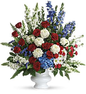 With Distinction Bouquet - A dazzling display of patriotic red, white and blue flowers sends a silent yet poignant statement about hope, freedom and the strength to endure. This proud bouquet is a testament to life that is sure to be appreciated. A beautiful mix of all-American red, white and blue flowers such as hydrangea, roses, miniature carnations, snapdragons, chrysanthemums and more are perfectly arranged in a white urn. Approximately 31" W x 34 1/2" H