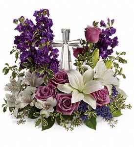 Teleflora's Grace And Majesty Bouquet DX - A bouquet to remember. This glorious garden of roses, lilies and alstroemeria surrounds a gleaming Crystal Cross. It's a radiant, reverent expression of faith that will be appreciated for years to come. Lavender roses, white asiatic lilies, white alstroemeria, purple stock and purple seafoam statice are arranged with fresh pitta negra, seeded eucalyptus and lemon leaf. Delivered with a Crystal Cross keepsake. Approximately 16 1/2" W x 14 3/4" H