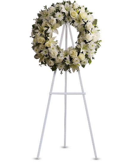 Serenity Wreath - Fragrant and ethereal white blossoms set among a ring of soothing greens form a classic wreath certain to evoke the pure heart and gentle spirit of a loved one - and offer consolation during a funeral or wake. Delivered on an easel, a standing wreath comprising fresh flowers such as white roses, asiatic lilies, carnations and chrysanthemums, as well as greens including salal, oregonia and dusty miller. Approximately 22" W x 22" H This item is hand-arranged and delivered by our florist. All prices in U.S. Dollars.