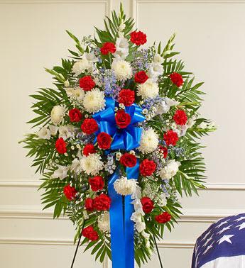 Deepest Sympathy Standing Spray - Red/White/Blue - This Sympathy Standing Spray, in red, white and blue, is a beautiful reflection of your patriotism, sympathy and support.  Red, white and blue flowers such as roses, football mums, gladiolas, delphiniums, carnations and more An appropriate gift for family, friends and business associates to send directly to the funeral home Due to the urgency of the occasion, our florists use only the freshest flowers available, so colors and varieties may vary Measures approximately 34"H x 40"L without easel