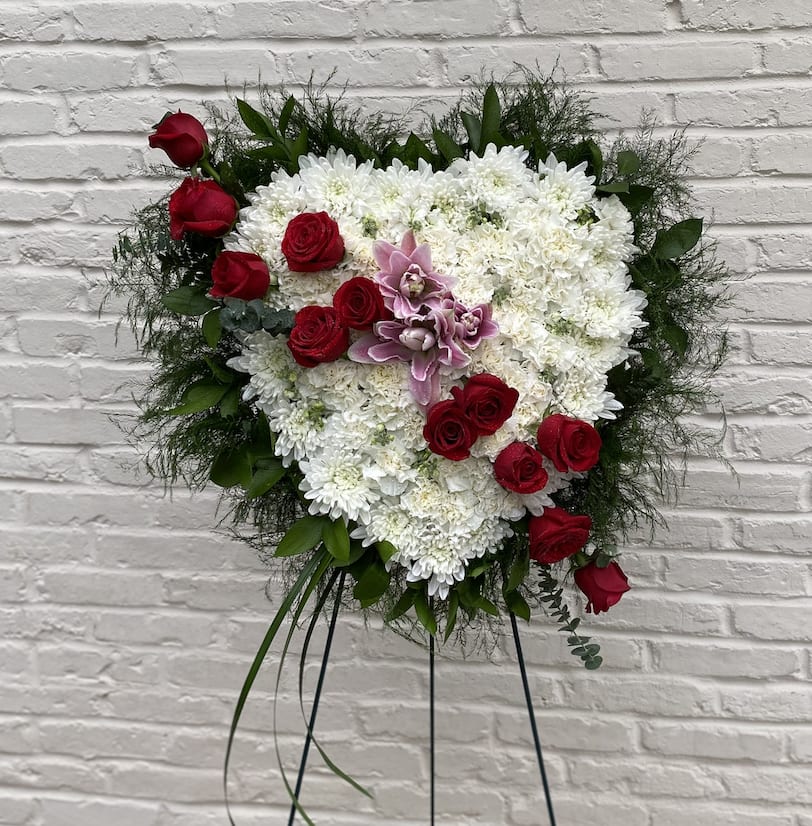 True Heart Standing Spray - Show that your heart is with them – send a gift of hope, beauty and devotion. This lovely standing spray of white blossoms in the shape of a heart is adorned with pink lilies and a dozen fresh red roses.