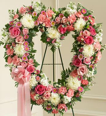 Always Remember Floral Heart Tribute - Pink - Convey your deepest condolences and undying love with this beautiful arrangement.  Pink and white flowers such as roses, stock, carnations and more Open heart with oasis in mache, tied to the wire easel with satin ribbon Sent directly to the funeral home by family and friends Our florists use only the freshest flowers available so components may vary Measures approximately 34"H x 32"L