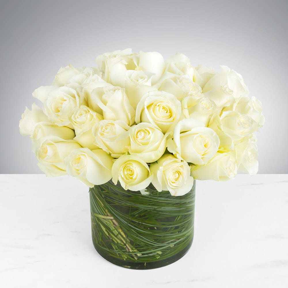 Two Dozen White Roses Modern - Make a bold statement with this elegantly simple design. White roses symbolize hope, honor, adoration, and innocence. Two Dozen White Roses by BloomNationâ¢ is the perfect gift to welcome new beginnings or show your respects.    Arrangement Details: Three dozen red roses in a glass cylinder vase.  APPROXIMATE DIMENSIONS are 11"D X 12"H