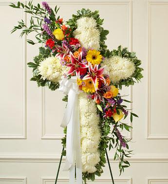 Peace and Prayers Standing Cross – Bright - This beautiful floral tribute shows your compassion, faith and love during this difficult time. This standing spray arrangement – in the shape of a cross – is created from fresh white mums and bright-colored roses, lilies, Gerbera daisies, carnations and more Traditionally sent directly to the funeral home by family members or friends and displayed on a stand Our florists use only the freshest flowers available so varieties and colors may vary Measures approximately 42"H x 28"L without easel