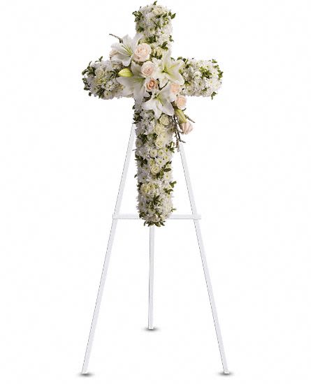 Divine Light - Steadfast devotion and hopes for eternal salvation are expressed with this gracefully elegant cross featuring a sash of white lilies. Your faith and sincere condolences will comfort the bereaved. Beautiful flowers such as crème roses, white spray roses, oriental lilies, stock, leptospermum, cushion and button spray chrysanthemums on an easel-mounted standing cross. Approximately 22 1/2" W x 36" H This item is hand-arranged and delivered by our florist. All prices in U.S. Dollars.