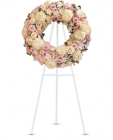 Peace Eternal Wreath - A pure and delicate expression of adoration. Accented with a sheer pink organza bow, this wreath of white, crème, and pale pink petals gently embraces loving memories, and offers solace and sweet thoughts at a time of loss. Lovely blooms such as crème and pink roses, pink hydrangea and white chrysanthemums are nestled together and accented with organza ribbon. A touching and feminine wreath, ideal for a memorial service. Approximately 24 1/2" W x 24 1/2" H This item is hand-arranged and delivered by our florist. All prices in U.S. Dollars.