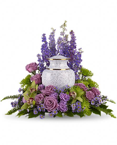 Meadows of Memories - As you come together to share your memories, these assorted purple flowers cradle the urn in a loving embrace. The soft greens and soothing purples are ideal to grace a memorial service. Includes lovely flowers such as lavender larkspur, roses, carnations and asters, plus, green cymbidium orchids and fuji chrysanthemums.Please note: Arrangement does not include urn. Approximately 23 1/2" W x 20" H This item is hand-arranged and delivered by our florist. All prices in U.S. Dollars.