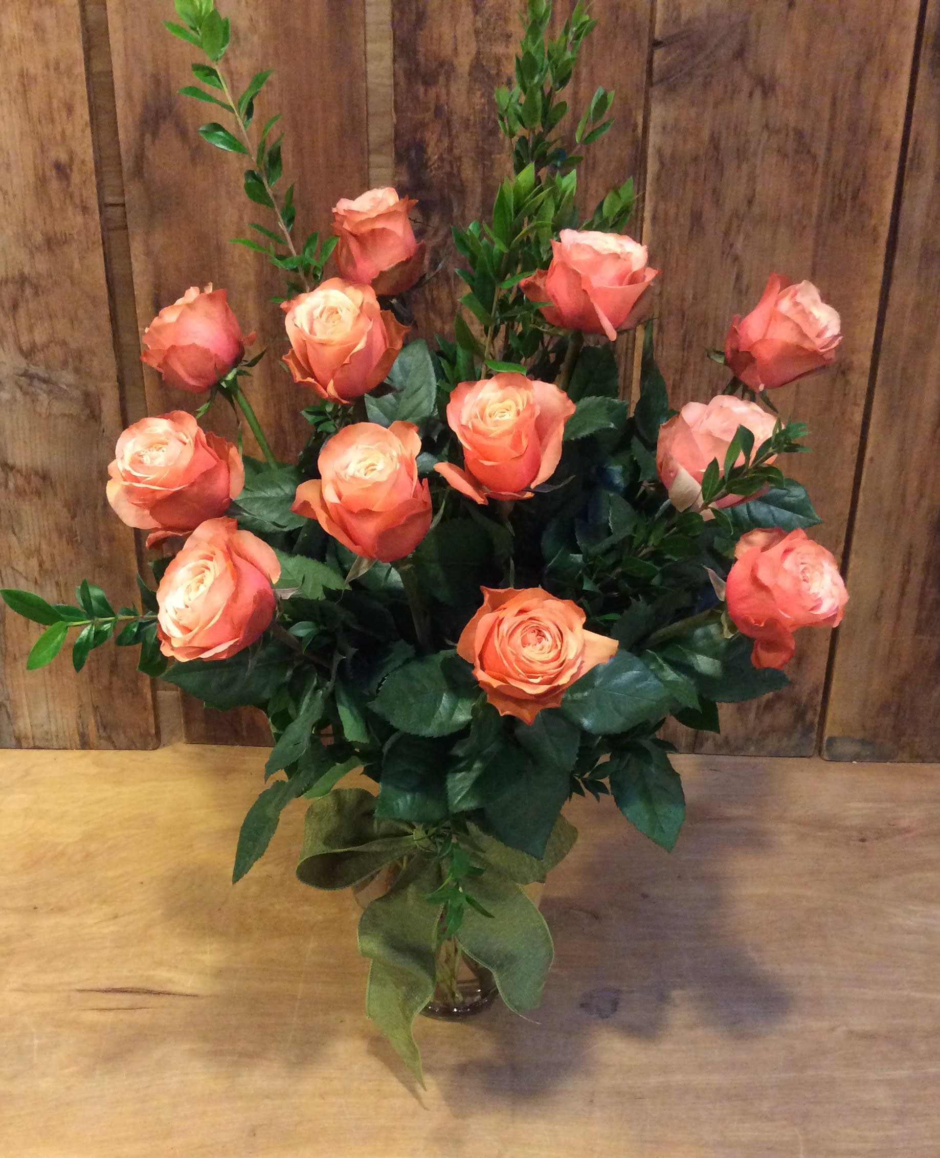 long peach roses  - Just Peachy!!! These peach roses open up to reveal a soft peach center just like a garden rose. A sure delight!!! A dozen roses with premium mix greens are arranged in a classic urn vase and finished with a ribbon. All our roses are open cut roses, which means they are on the plant longer. This allows them to be a stronger cut flower and have a longer vase life.