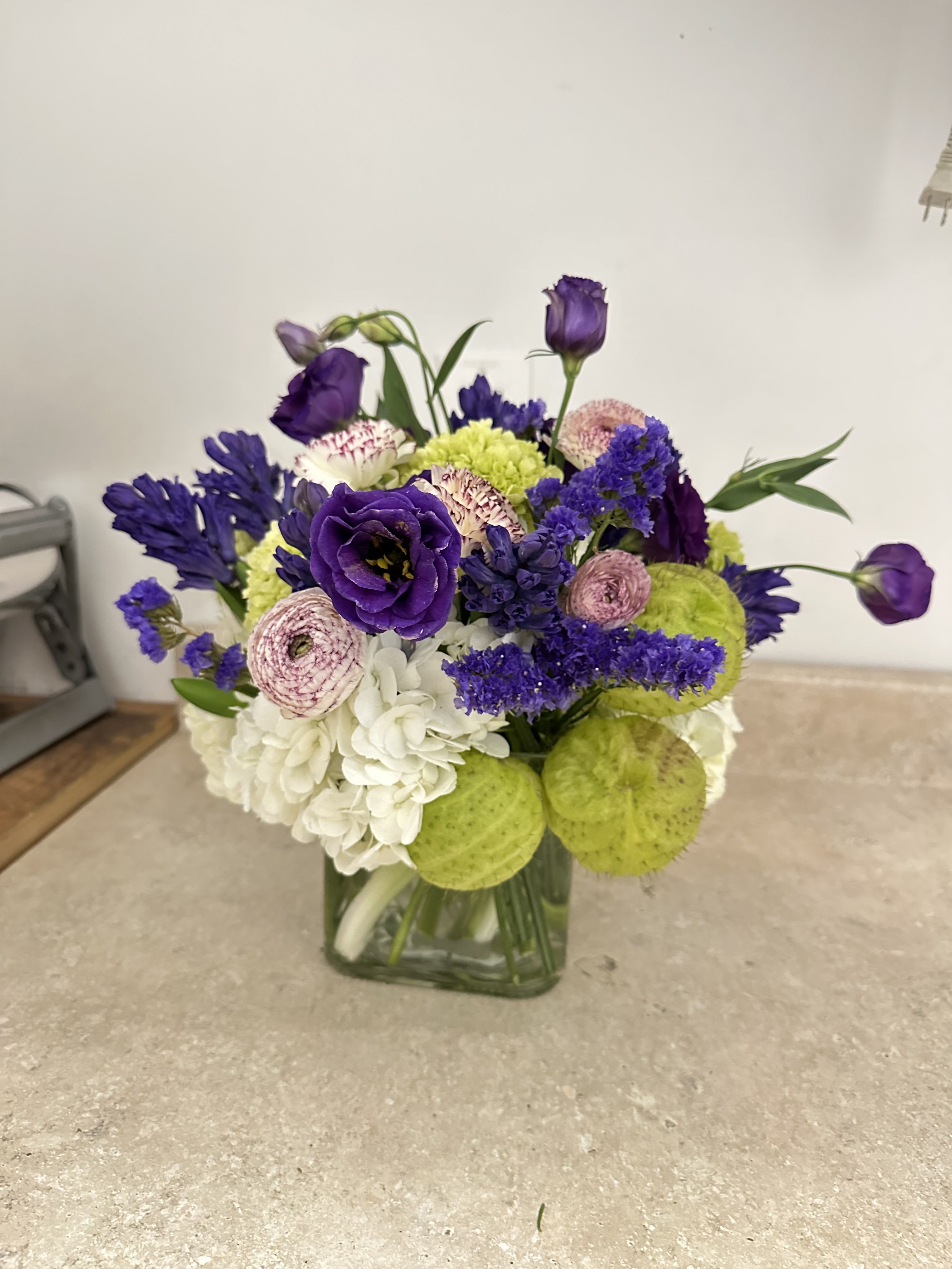 LITTLE SMILE - Unique white and purple colors, the perfect color combination with a touch of green. Cotton bush with globe, with a touch of purple ranunculus and purple lisianthus, and Hyacinth impressive arrangement that makes you SMILE.