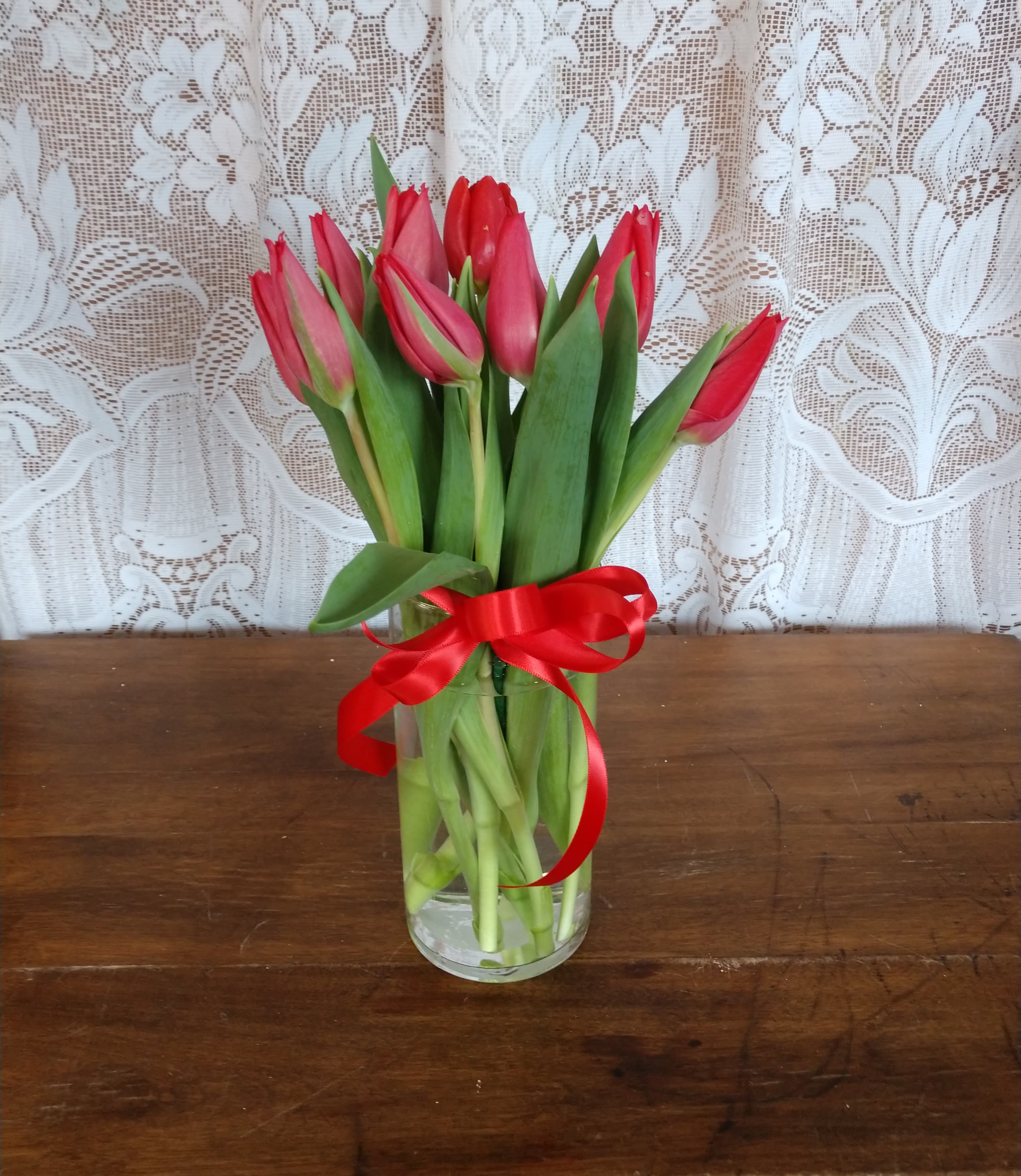 Radiant Red Tulips - Red Tulips arranged in a glass vase.