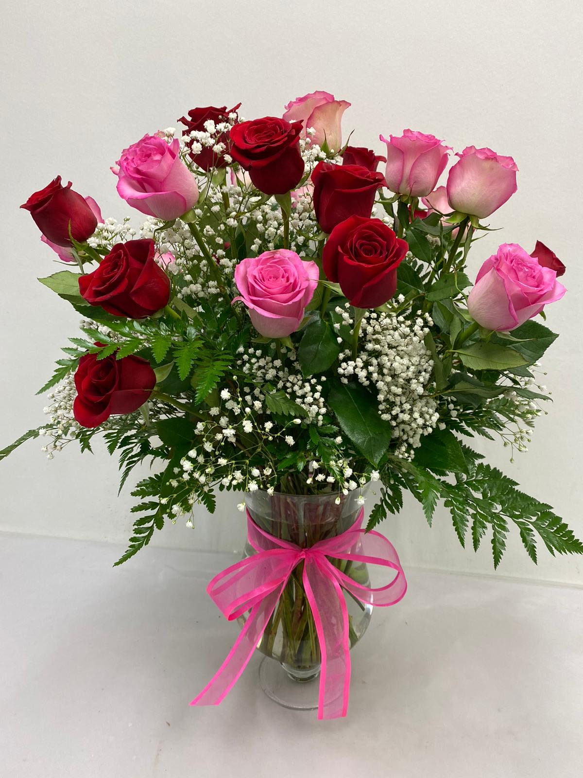 Mixed 2 Dozen Roses (Red + Pink) - Premium two dozen red + pink roses along with baby's breath and greenery in classic footed glass vase.
