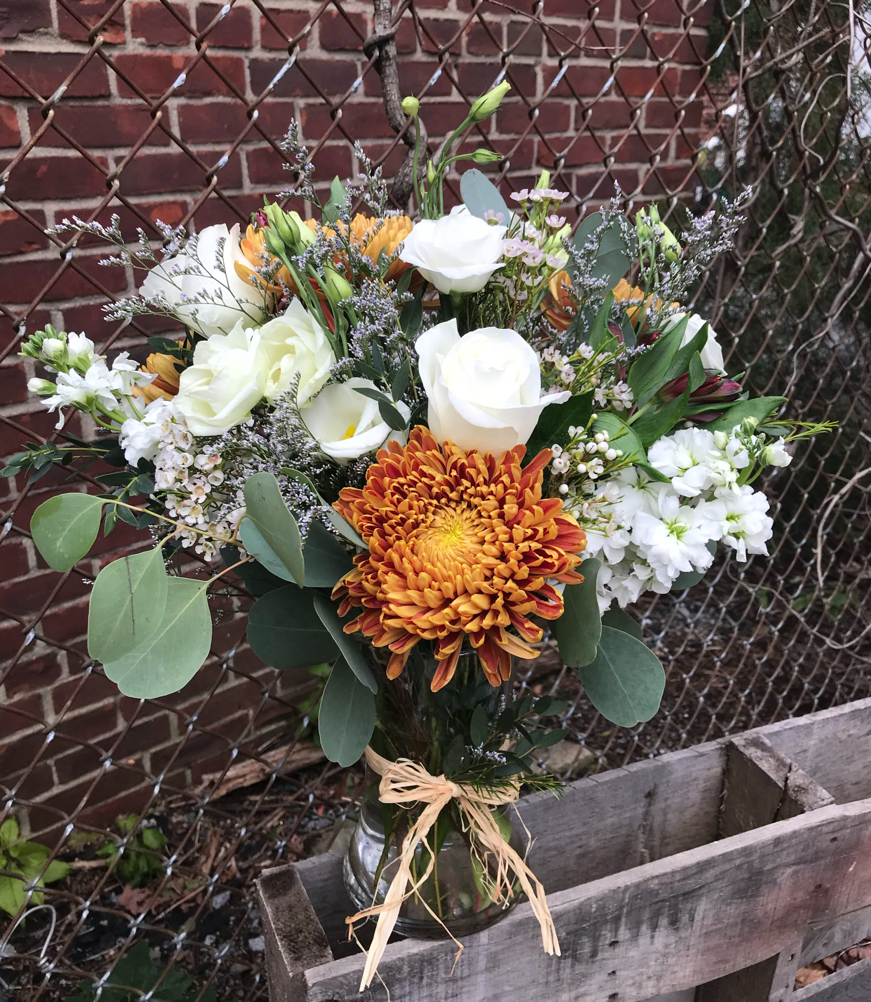 Meadow Vase - Seasonal chrysanthemums, eucalyptus, stock and fresh white wildflowers offer a lightly fragrant scent.  Flowers that look as if they were just picked from the meadow in a gathering vase and raffia tie.  