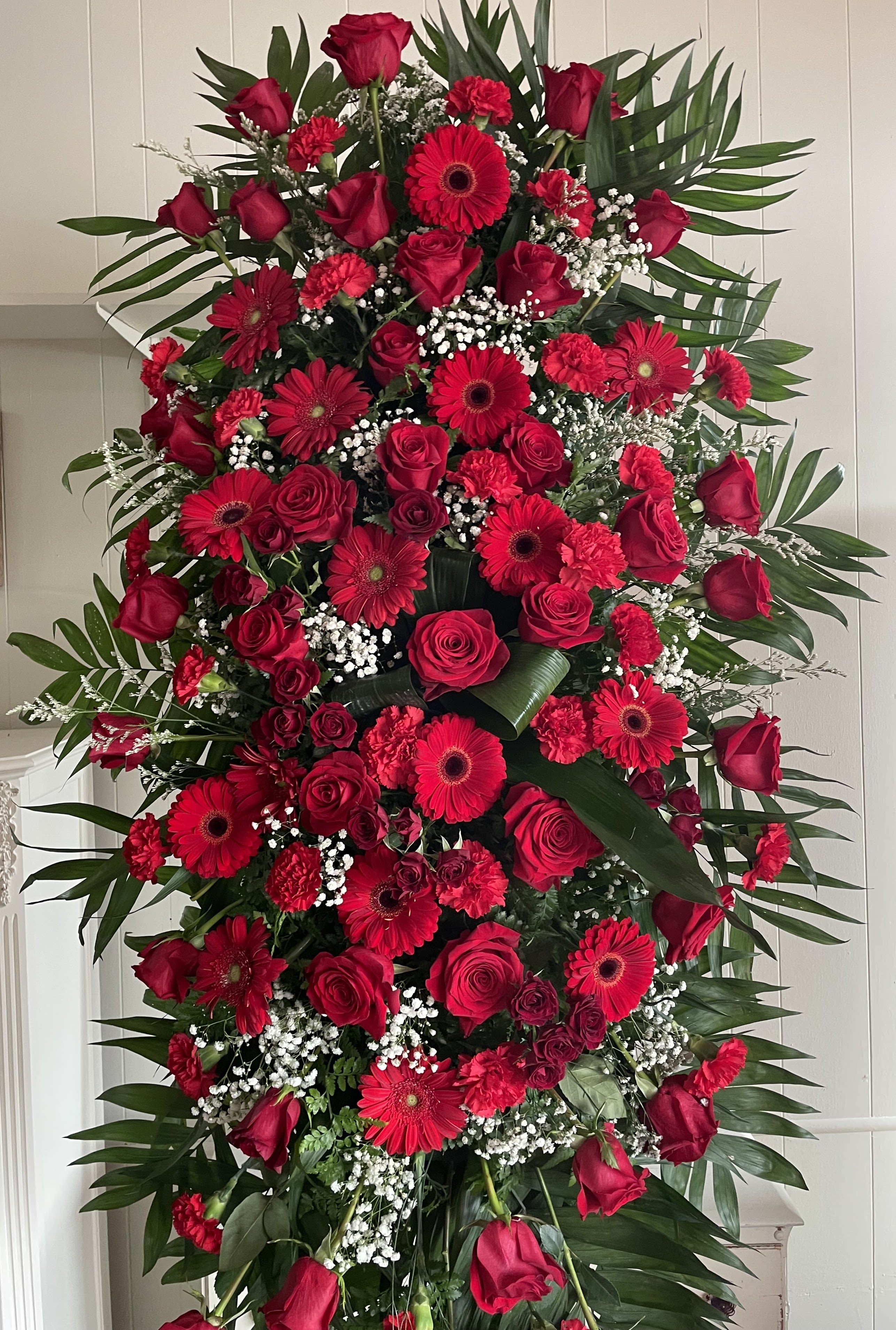 Compassion Spray  - Your care and compassion will be appreciated by all who lay eyes on this radiant standing spray. A variety of lovely vibrant red blossoms contrasted by vivid greenery  will deliver your heartfelt condolences. Perfectly. 