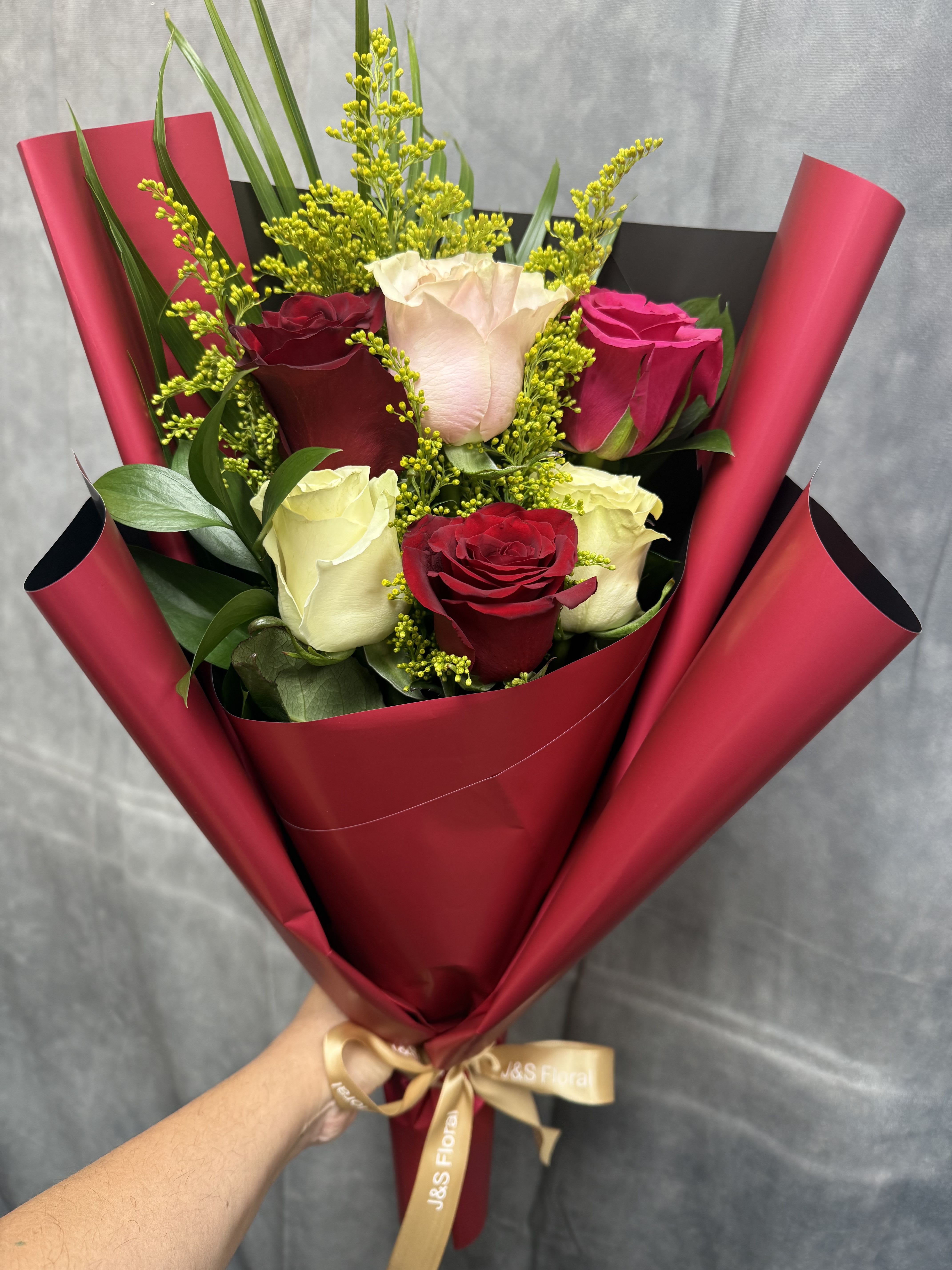 Mix Layed Roses Bouquet  - A classic and elegant rose bouquet featuring a beautiful mix of red, blush, and ivory roses, accented with fresh greenery and delicate fillers, all wrapped in a rich burgundy wrap and finished with our signature ribbon—perfect for expressing love, appreciation, or a timeless gesture. 