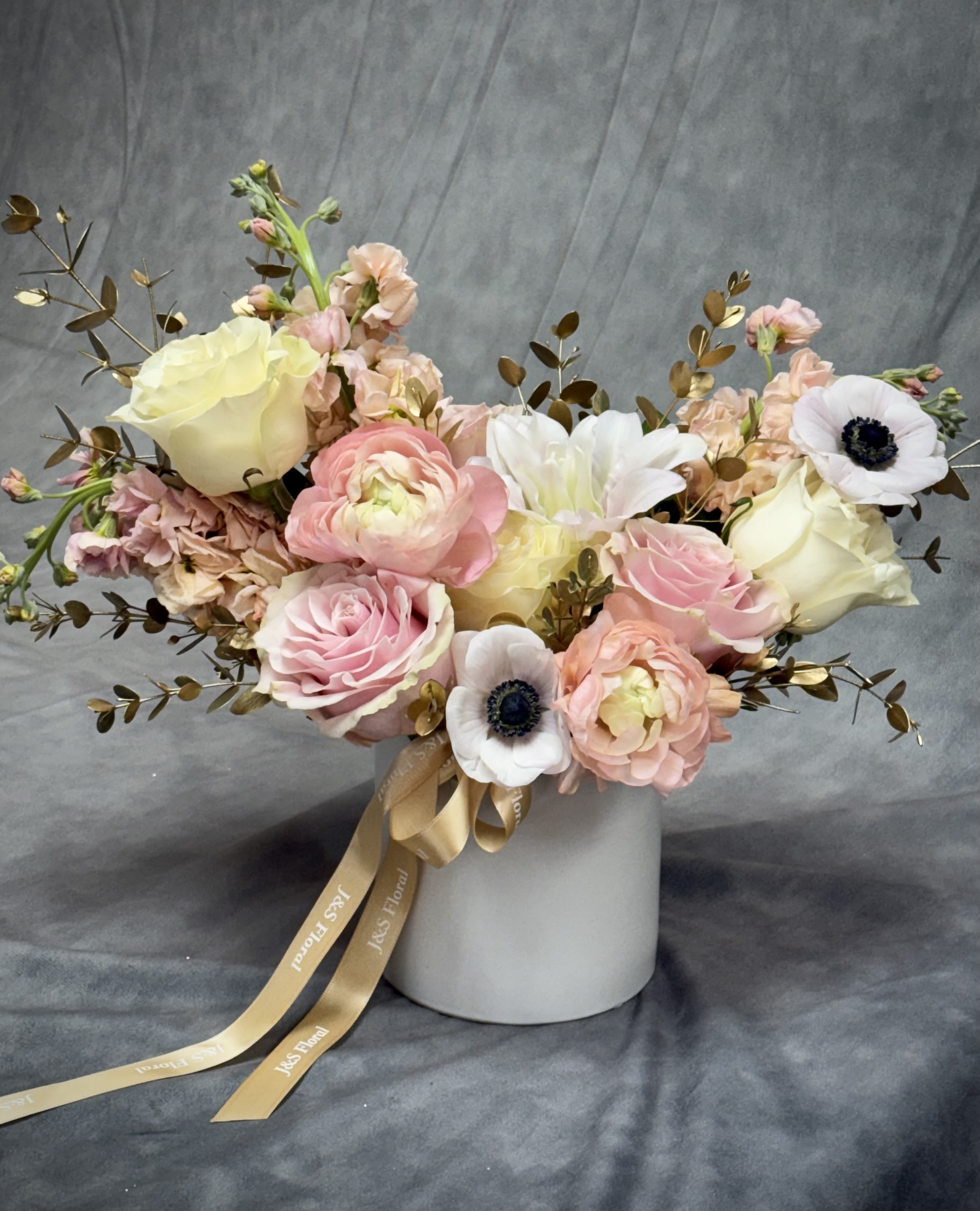 Golden Grace - Golden Grace Soft blush, ivory, and peach blooms paired with golden accents create a look of timeless elegance. Arranged in a sleek ceramic vase, this design adds warmth and sophistication to any occasion.