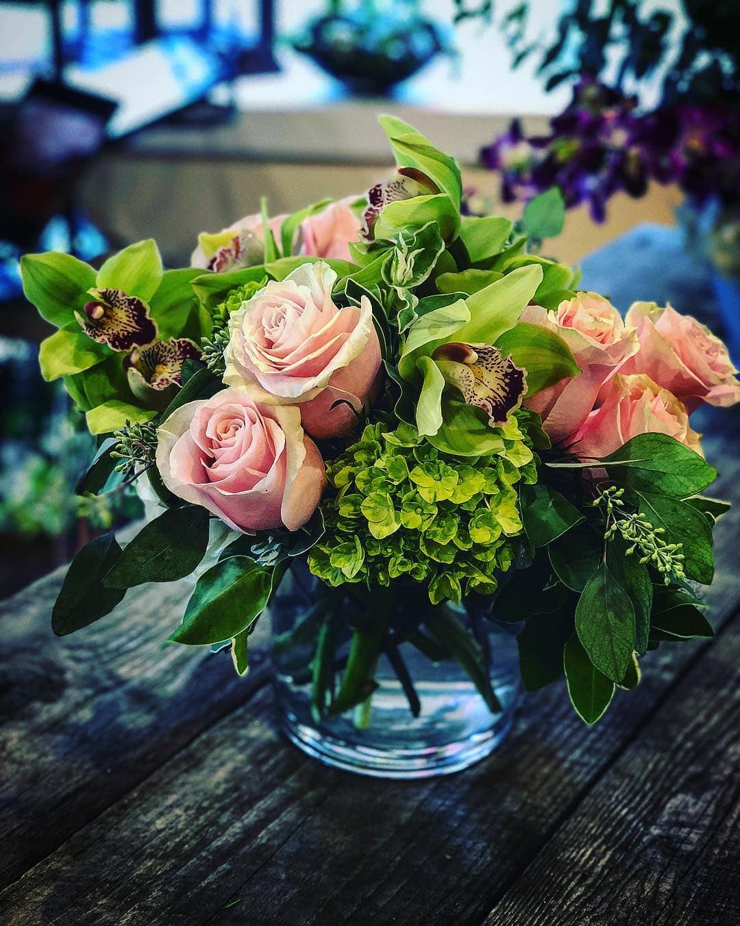 Love Ya! - A soft elegant arrangement of ice pink roses and green cymbidium orchids.  Accented with eye catching green hydrangea, designed in a short glass cylinder.  One of our favorite designs to send out.  A fan favorite for sure.