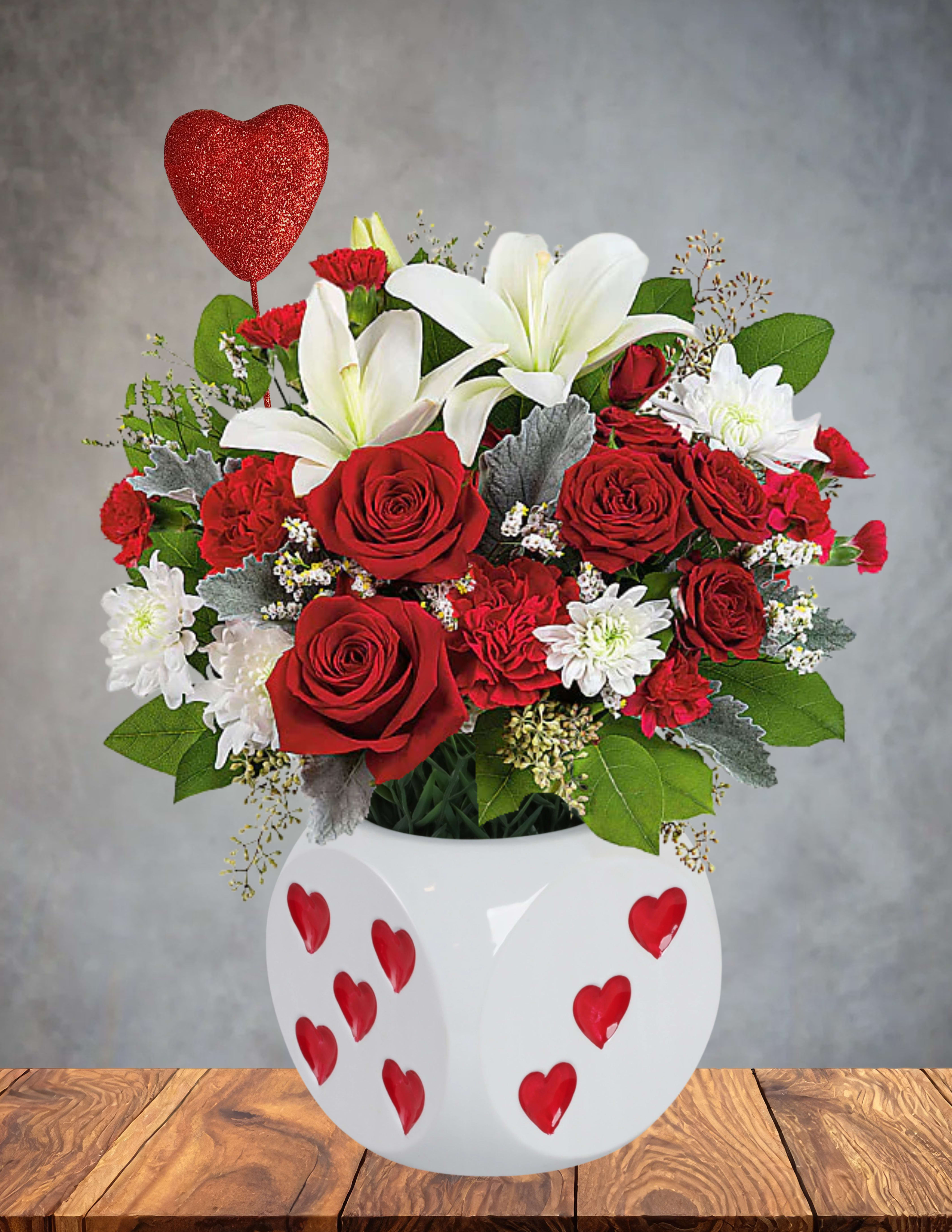 High Stakes Romance - ️ High Stakes Romance   Turn up the passion with a bouquet that knows how to make an entrance. High Stakes Romance blends the elegance of snowy white lilies with the deep, velvety richness of red roses, accented by lush red and white chrysanthemums for added texture and fullness.  Arranged in a striking heart‑shaped dice vase, this design is all about taking a chance on love—and winning big. Perfect for anniversaries, bold romantic gestures, or anyone who loves a little drama with their devotion.