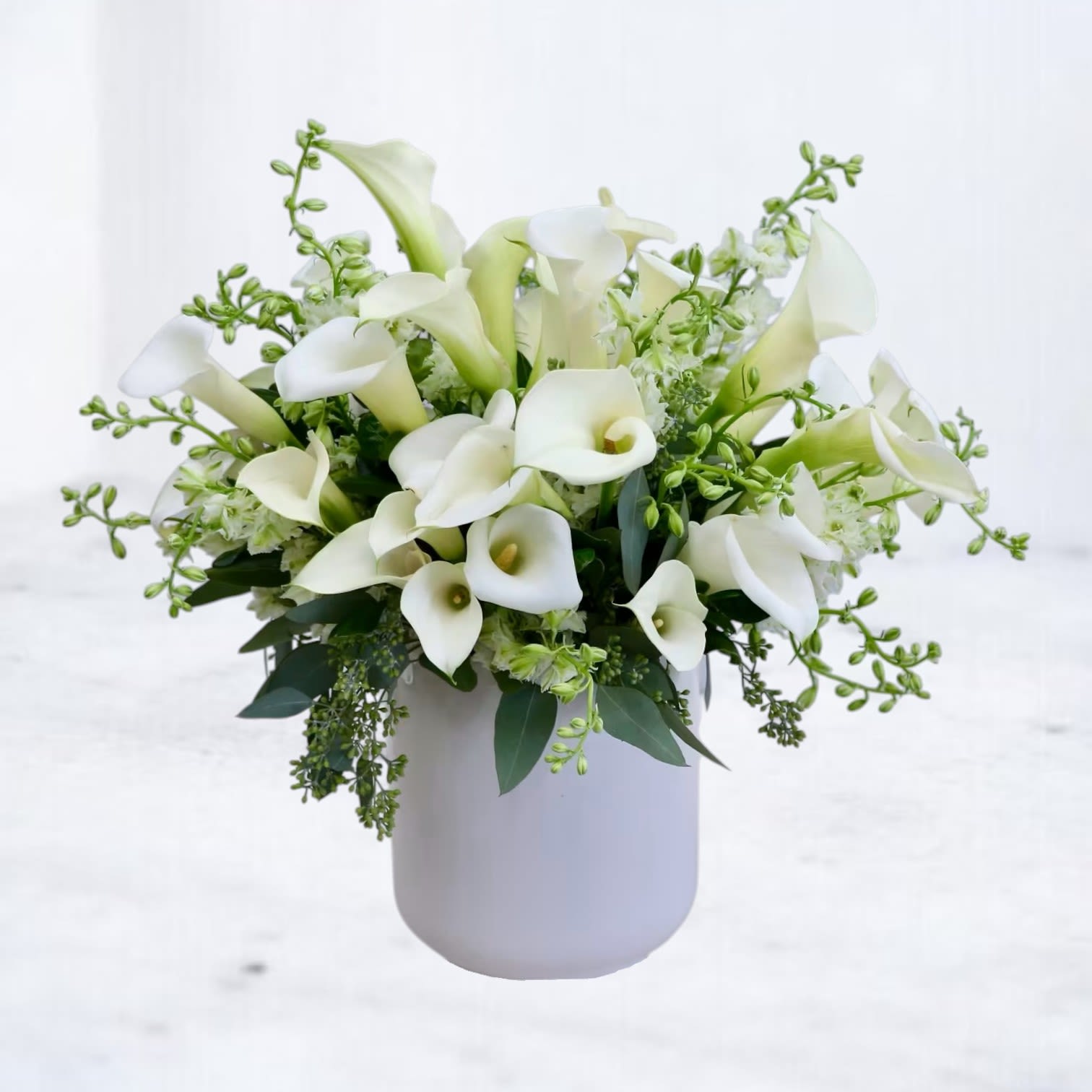 Line &amp; Form - Line &amp; Form is a modern floral arrangement defined by sculptural shape, movement, and restraint. Featuring elegant white calla lilies layered with soft white seasonal blooms and fresh green accents, this design emphasizes clean lines and natural negative space. Styled in a smooth, minimalist ceramic vessel, it feels architectural, refined, and quietly striking.  Perfect for modern interiors, sympathy gestures, professional gifting, or anyone drawn to a calm, contemporary aesthetic.  Flower varieties may vary slightly based on seasonal availability to ensure the freshest blooms while maintaining the overall form, palette, and modern design.