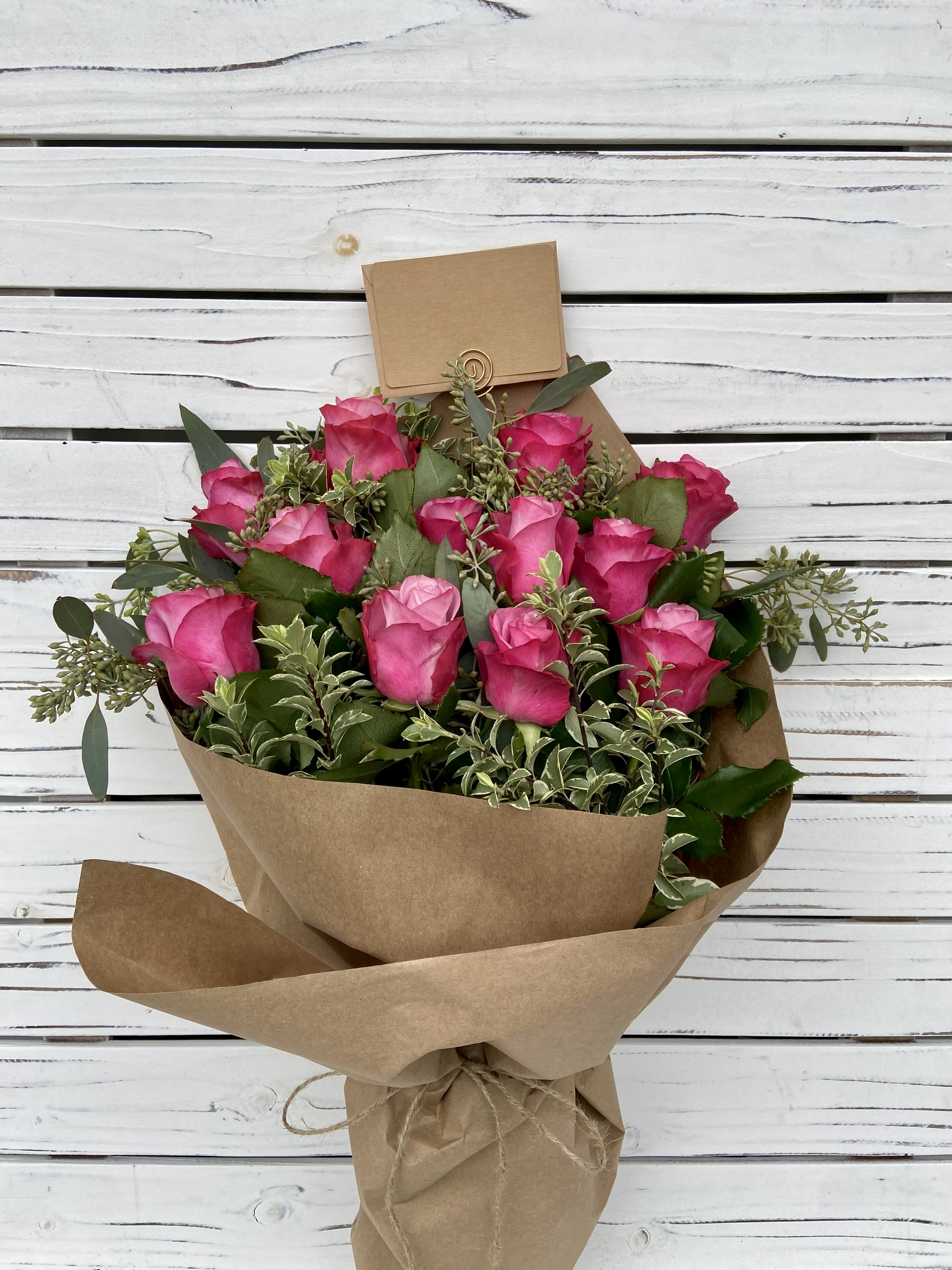 1 Dozen Pink Rose Bouquet - Shade of pink color and greens may vary. Brown Paper Bouquet comes with a moisture pak and is wrapped in brown paper and tied with twine.  
