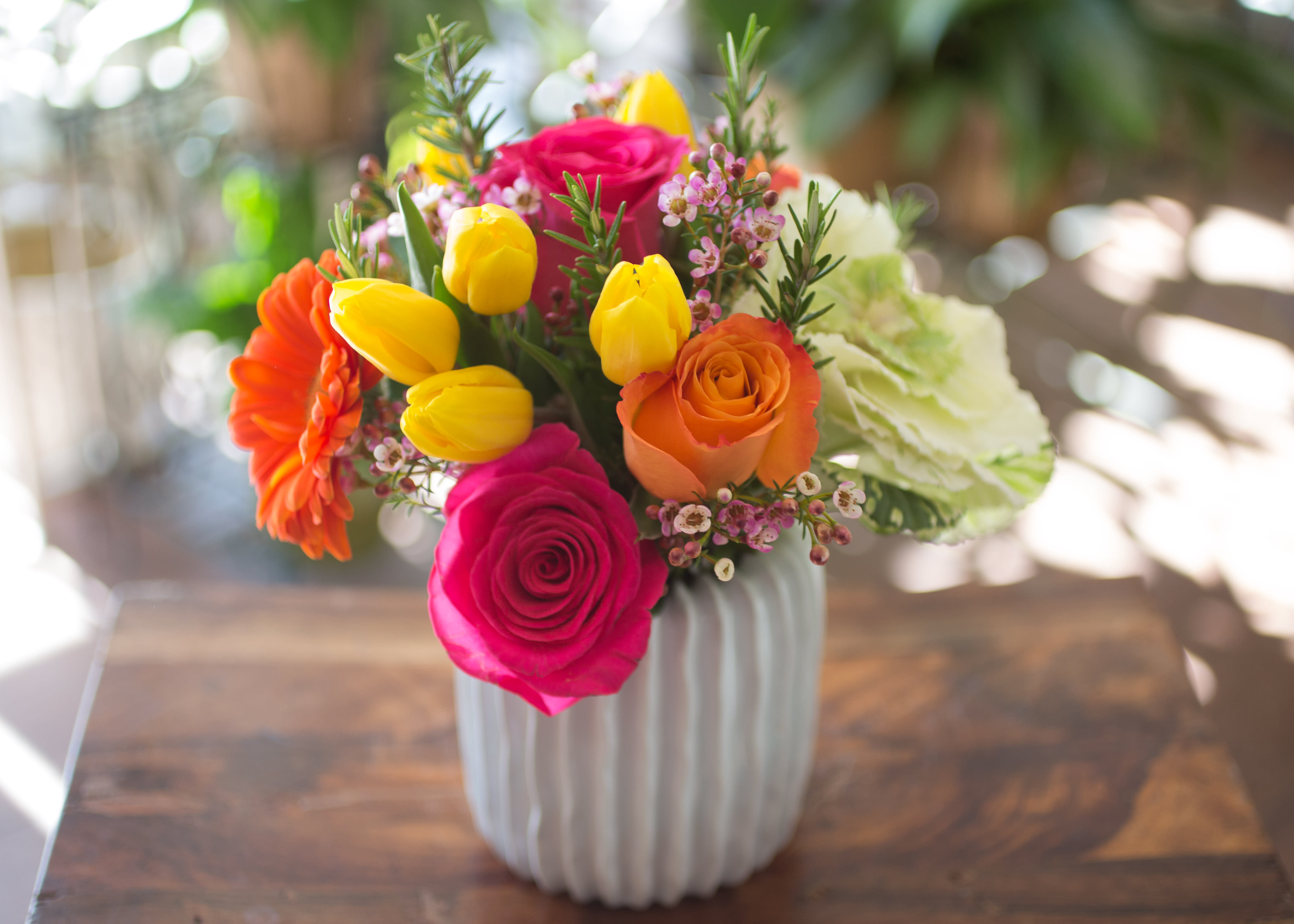 Abella - Spring with Tulips, Kale, Roses and Gerbera Daisies arranged in a ceramic vase.