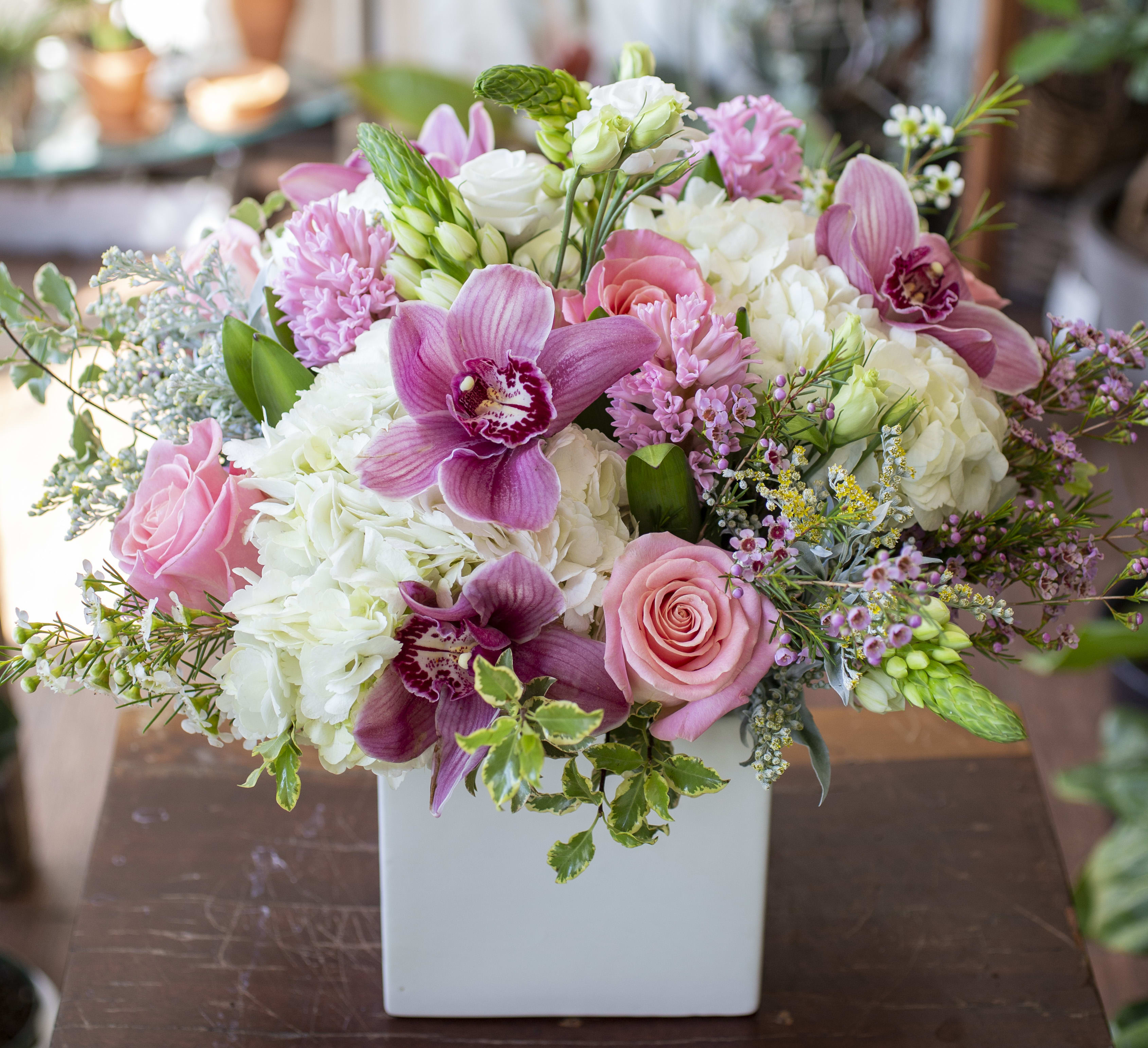 Olivia - Assortment of seasonal flowers in white and shades of pink, arranged in a ceramic container. 