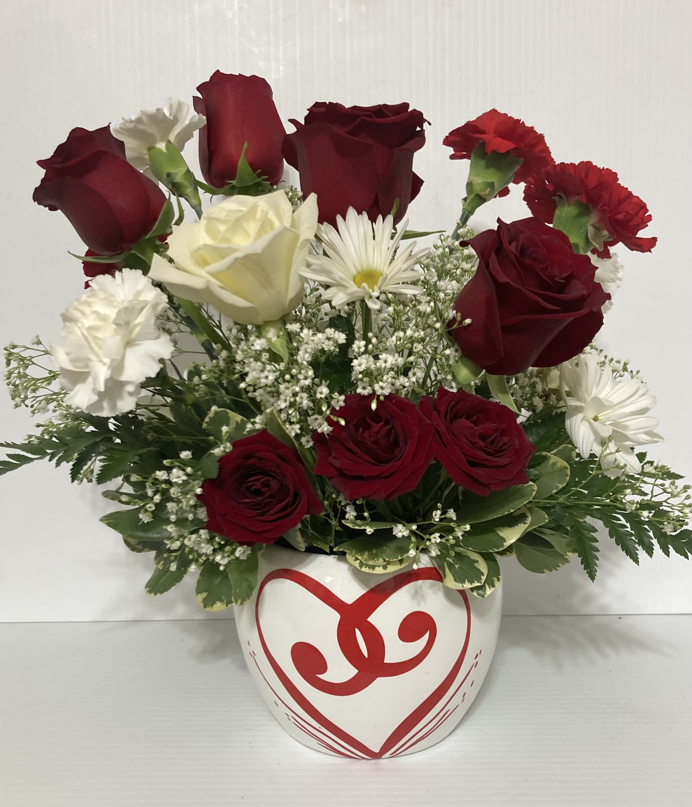 Red Romance - Beautiful arrangement with Roses, Carnations, greens in a decorative heart vase