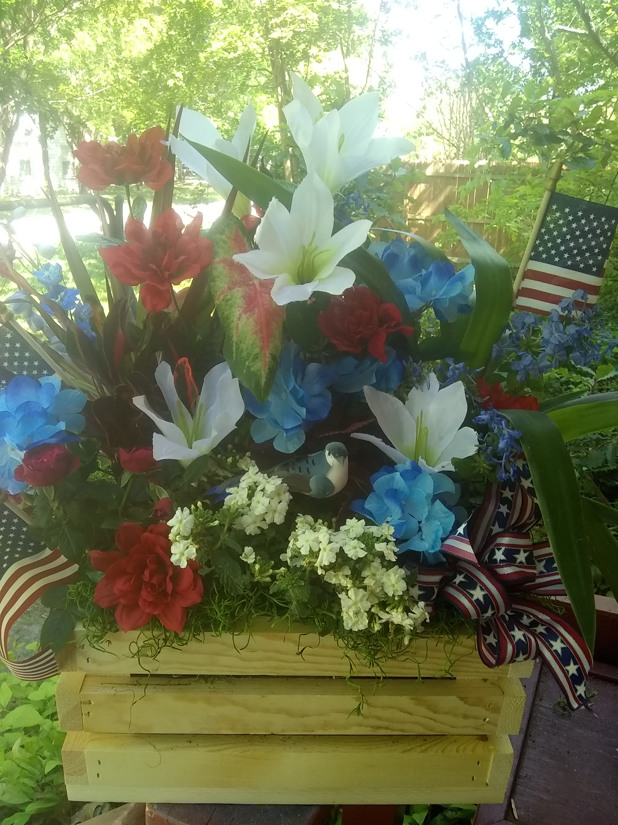 Freedom Flower Planter - A natural wood crate full of a nice variety of low maintenance green house plants and silk flowers added in with birds and small American flags for a very fun festive patriotic look and good for many different occasions such as Memorial Day, 4th of July, Labor Day and to send to the family at their loved one's memorial service or to their home for a sympathy gift in honor and remembrance of their precious loved one