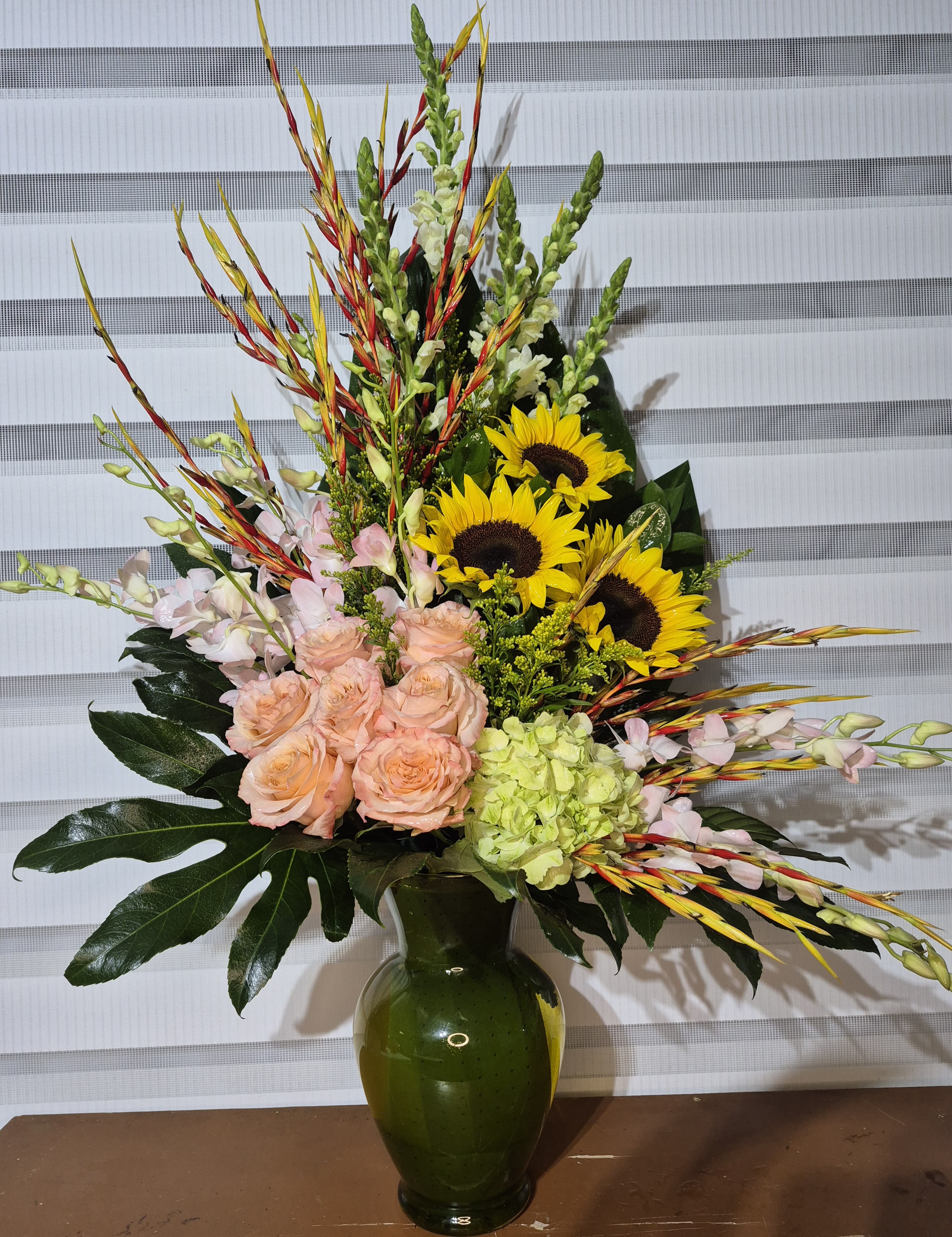 SUNFLOWER RHAPSODY - ONESIDED TALL ARRANGEMENT IN A 11 INCH TALL GLASS VASE, CONSISTING OF FLOWERS SUCH AS YELLOW SUNFLOWERS, PEACH ROSES, WHITE HYDRANGIAS, PINK/WHITE DENDROBRIUM ORCHIDSAND YELLOW SOLIDAGO FILLER.
