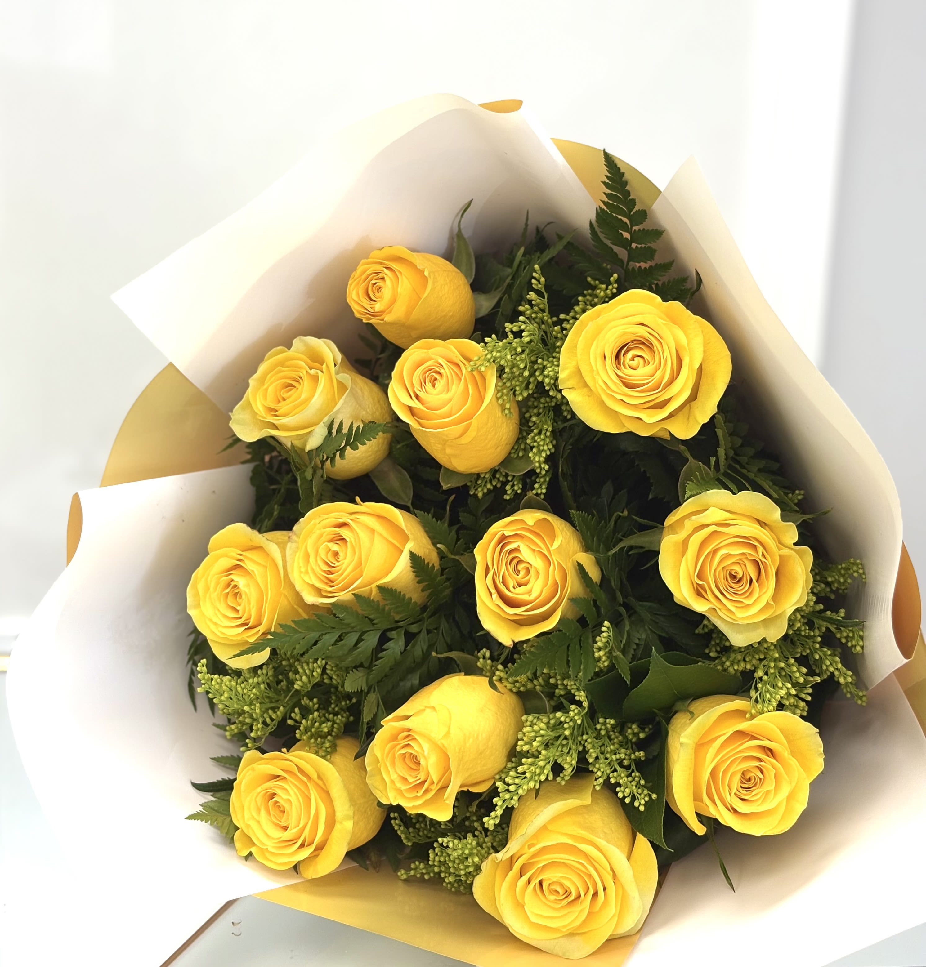 Sunshine Whisper By VLM Flowers - A radiant arrangement of sunny yellow roses and delicate greenery, this bouquet brings light and happiness with every petal.