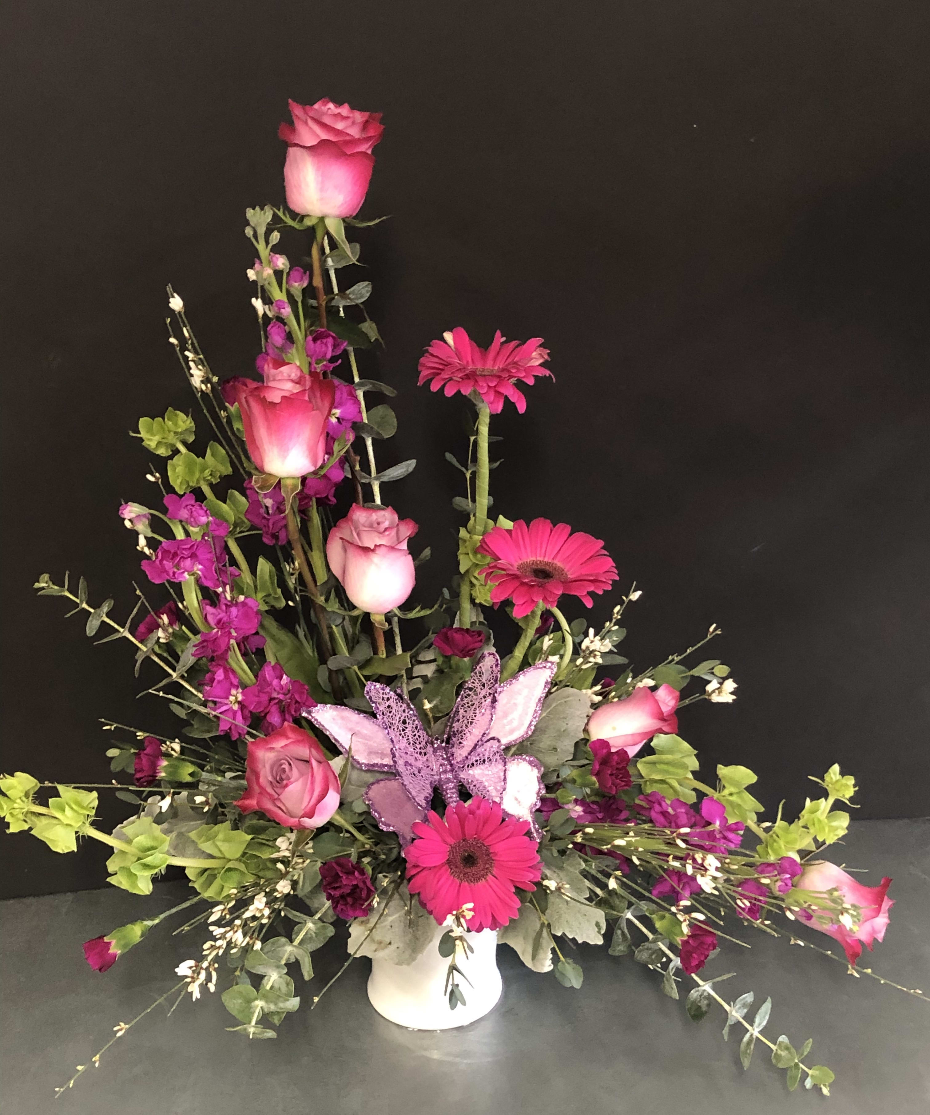 Flutter by Butterfly - Gerberas, Roses, stock, bells of Ireland, eucalyptus, spray carnations, accented with a butterfly. Can customize the color of the flowers and butterfly.
