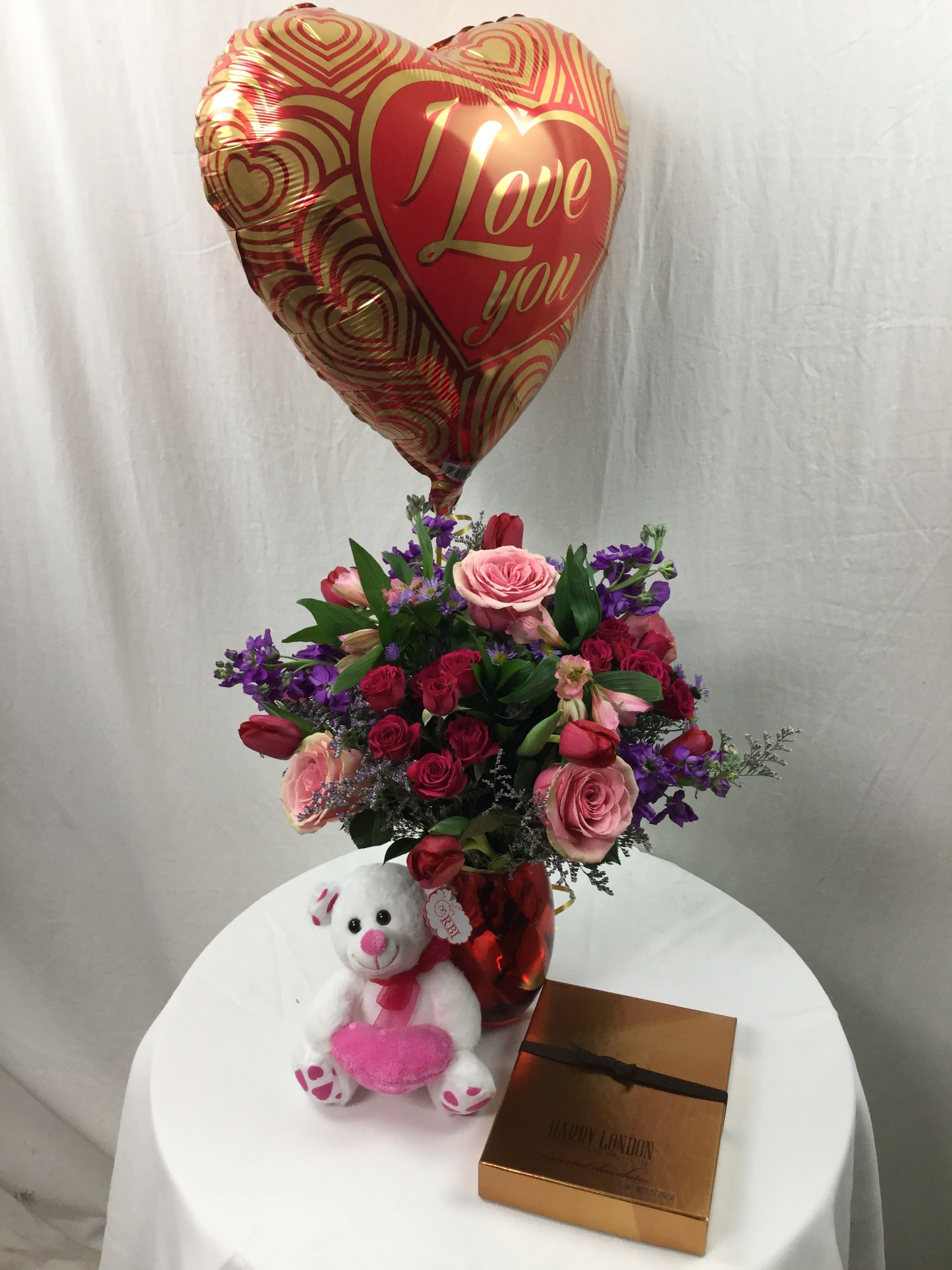 Be Mine Bundle - The perfect gift and so much more. This bundle includes a stunning vase arrangement hand-crafted and designed in a keepsake vase, a plush bear, a box of chocolate, and a mylar balloon. Makes for a wonderful gift for those special romantic occasions!