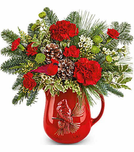 Festive Flight Bouquet - This charming cardinal pitcher is filled to the brim with festive seasonal greenery and rich red blooms, coming together to make the perfect gift to send for the holidays! Even better, this stylish pitcher is food-safe and can be used in the home for years to come. Approximately 13 1/2 inches wide and 13 1/2 inches tall for the Standard size.