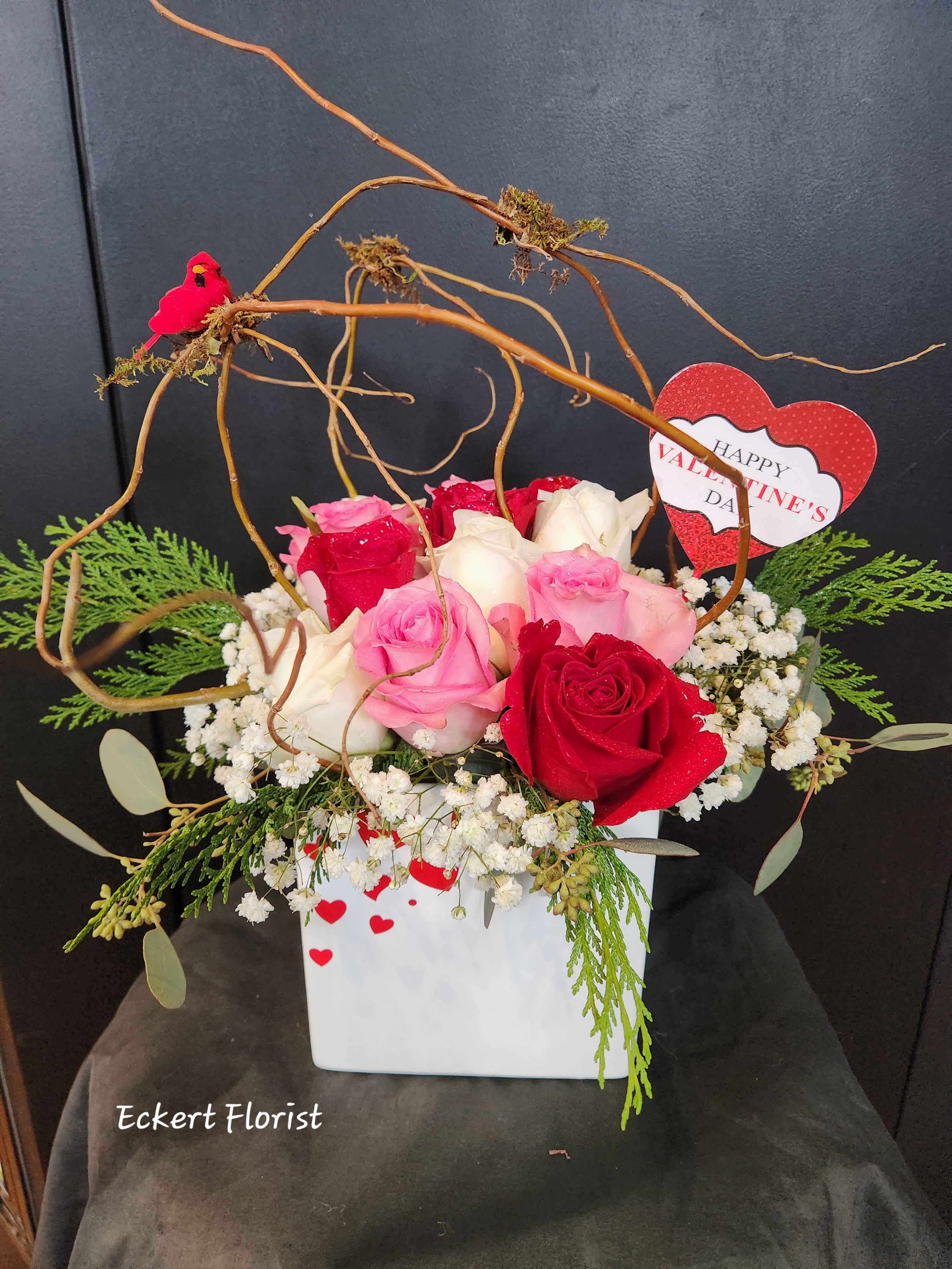 Eckert Florist's Fluttering Hearts Rose Cube *Our Local Delivery Only. - This bouquet will say "My heart flutters when I'm with you."  Designed in a ceramic cube (5.5" x 5.5" x 5.5"), this arrangement will arrive with 12 mixed colored roses, a nice Valentine pick and our signature bird and twig to give it a little finesse. *Color of roses may vary 