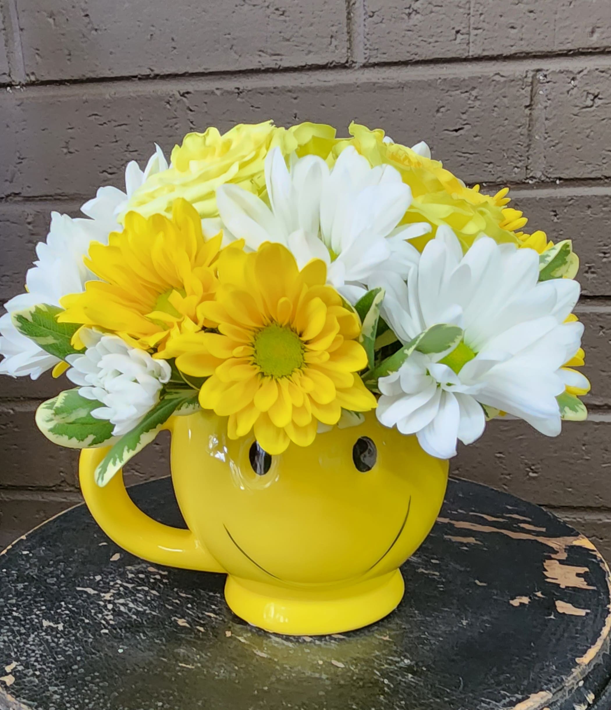 Carefree - The smiling mug is filled to the brim with 3 yellow roses, yellow and white daisies. It's so cute that whomever receives it is sure to smile, as well! 