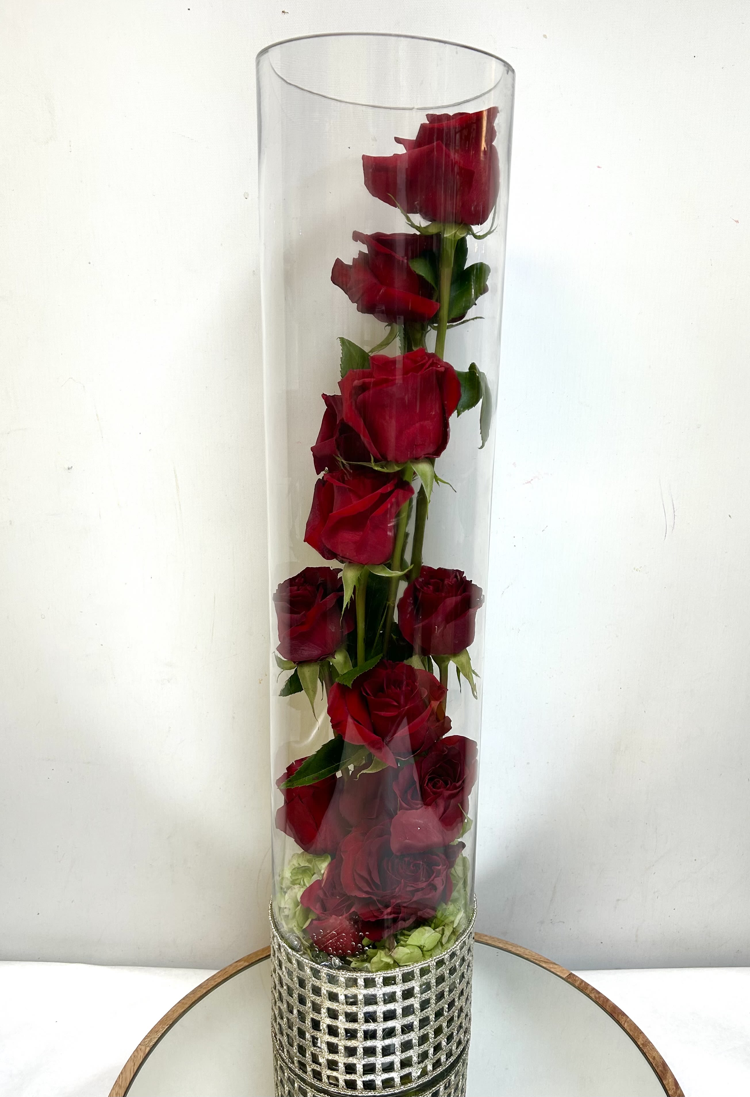 Forever In Bloom - Elevate any space with this striking arrangement featuring premium red roses artfully stacked within a sleek, extra-tall glass cylinder vase. This modern, architectural design emphasizes the natural beauty of each bloom, making it a sophisticated statement piece for a grand entryway or a contemporary centerpiece.
