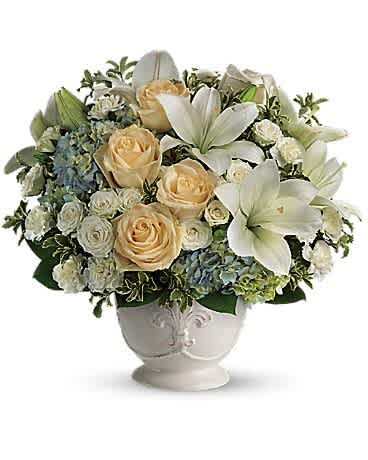 Ivory Elegance Bouquet - Graceful and timeless, our Ivory Elegance Bouquet is a stunning blend of cream roses, white lilies, spray roses, and soft hydrangea, all hand-designed in a classic white urn-style vase.  This serene arrangement is perfect for expressing heartfelt sympathy, celebrating weddings, anniversaries, or sending a sophisticated gift to someone special. Its neutral tones bring peace, comfort, and beauty to any space.  We proudly provide same-day flower delivery in The Colony, Frisco, Little Elm, Plano, Carrollton, Lewisville, and throughout the Dallas–Fort Worth area. Share your love, support, or congratulations with this refined floral design that speaks volumes in its quiet elegance.