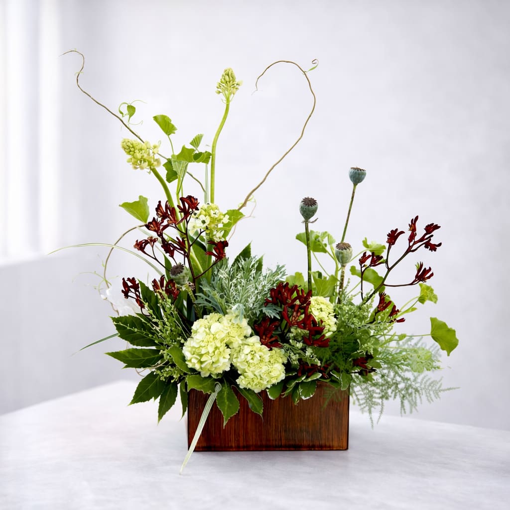 Midsummer Daydream - An earthy woodland fairy garden. With whimsical curly willow, dancing tendrils of dubium, playful kangaroo paw and poppy pods; framed with geranium, textural plumosa, lily grass and aralia. This is the perfect centerpiece for nature lovers or even something unique for a corporate event. Imagine an entire table scape with these magical details. "A daydream beneath the flowers."