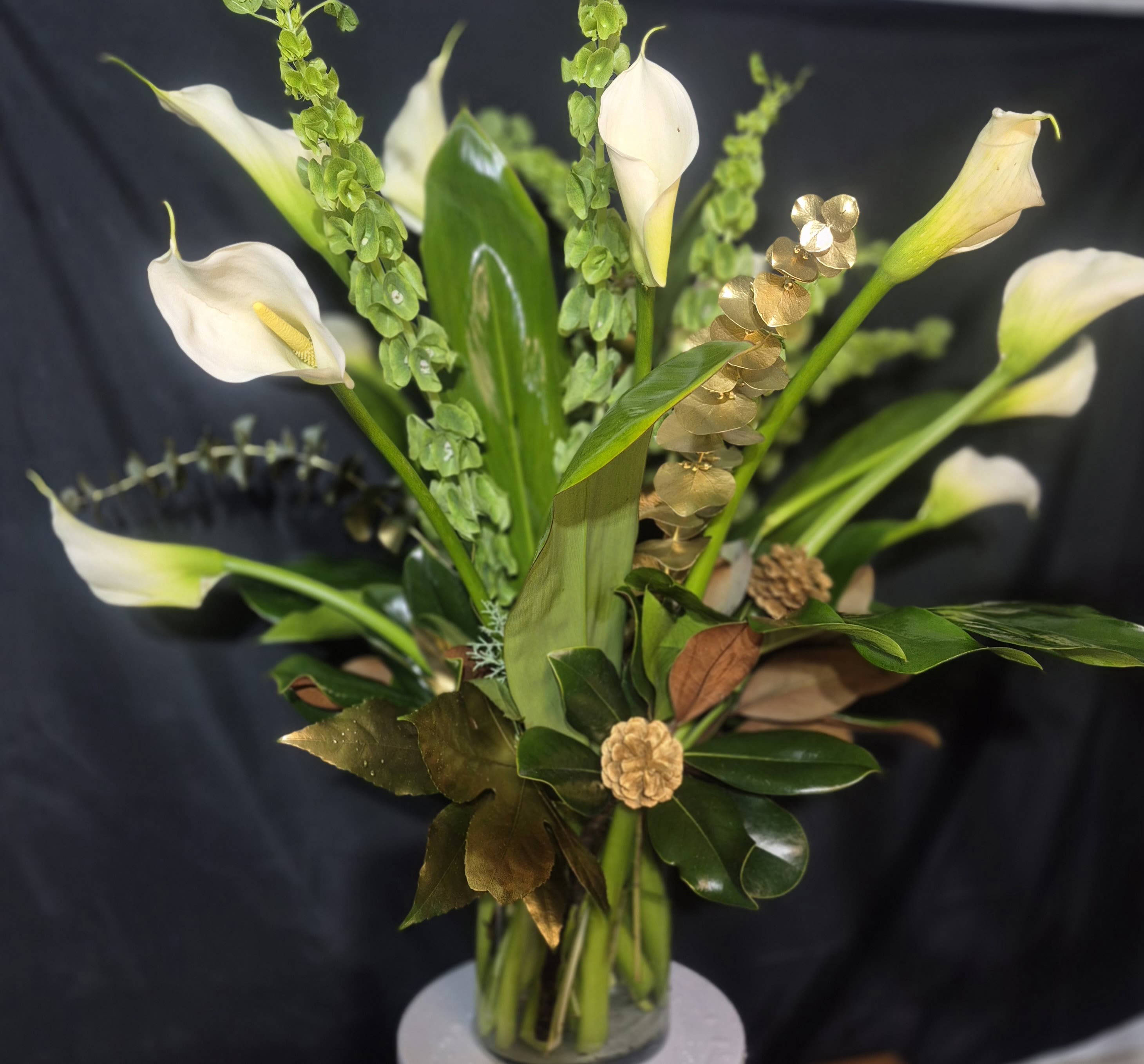 CALLA LILLY GALORE  - 15 EIGHTEEN INCH (18 INS) LONG STEMS OF PREMIUM WHITE CALLA LILLIES ELELIGANTLY ARRANGED ALL AROUND IN A 10 INC CLEAR GLASS VASE. ARRANGEMENT TO INCLUDE AN ASSORTMENT OF EXOTIC GREENS AND FILLER FLOWERS.